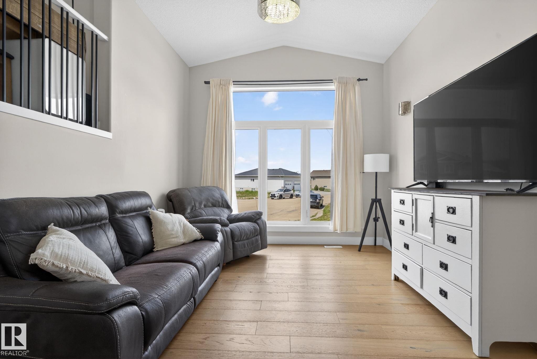 Open-concept living area with a vaulted ceiling and wood-finish flooring - 4204 55Av, Lamont, AB
