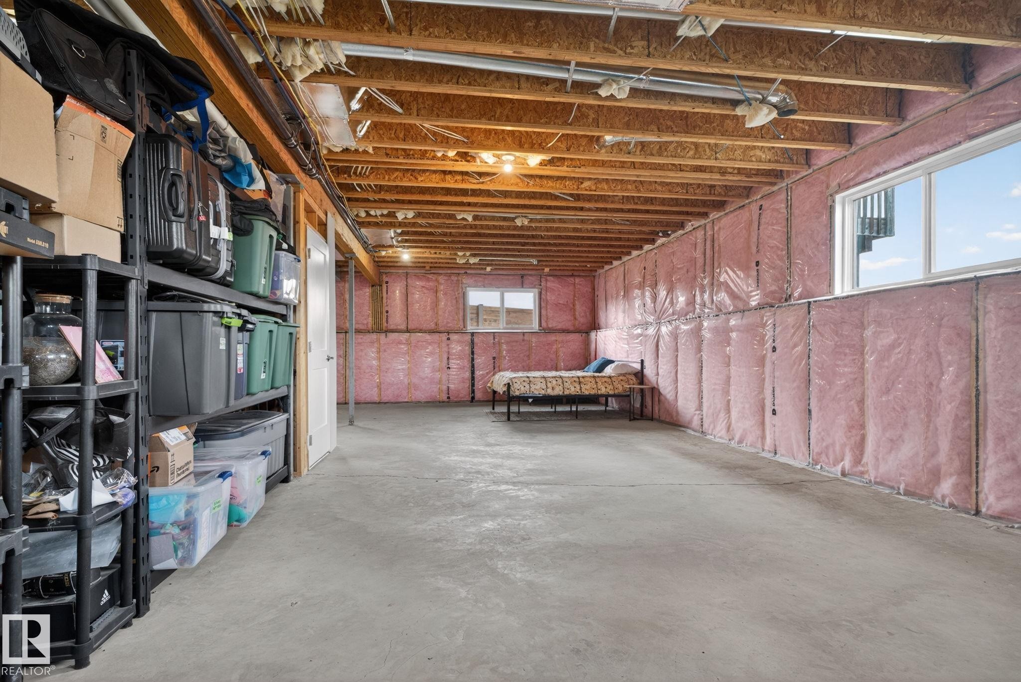 Unfinished basement space featuring exposed wood joists and subflooring, insulated perimeter walls, and concrete flooring - 4204 55Av, Lamont, AB