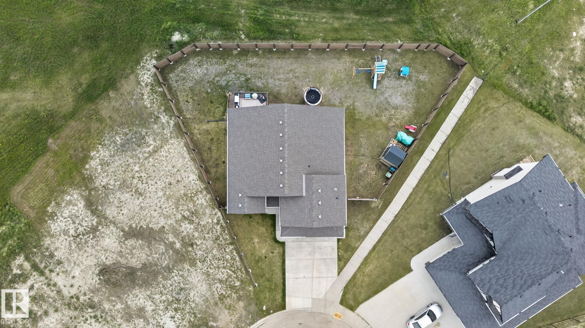 Gray shingle roof, concrete driveway, concrete sidewalk, wood fence enclosure, and surrounding green space - 4204 55Av, Lamont, AB