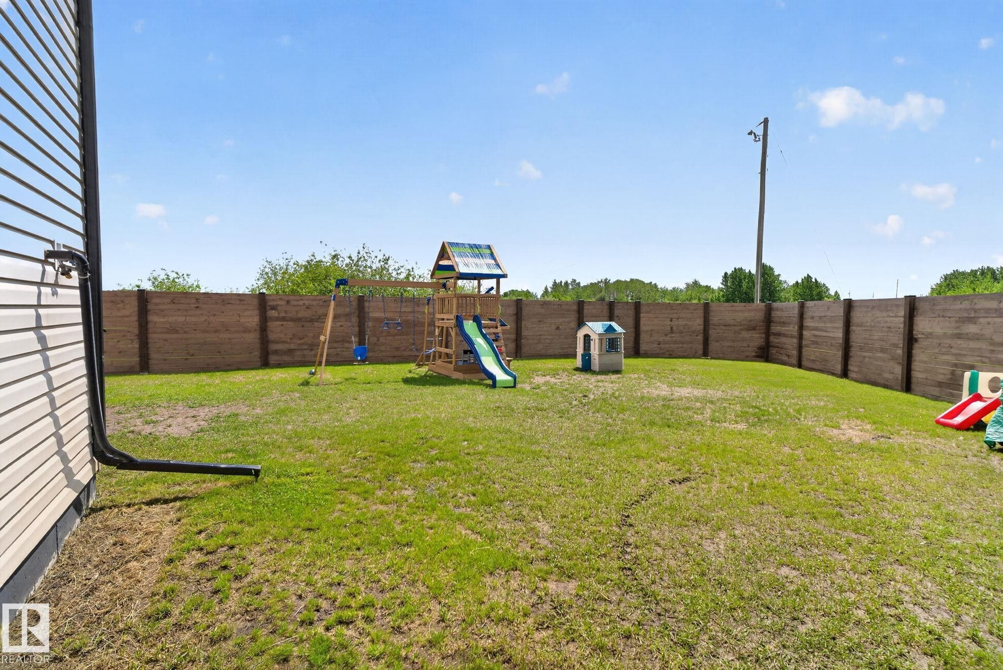 Expansive backyard featuring a full perimeter privacy fence and a verdant lawn - 4204 55Av, Lamont, AB