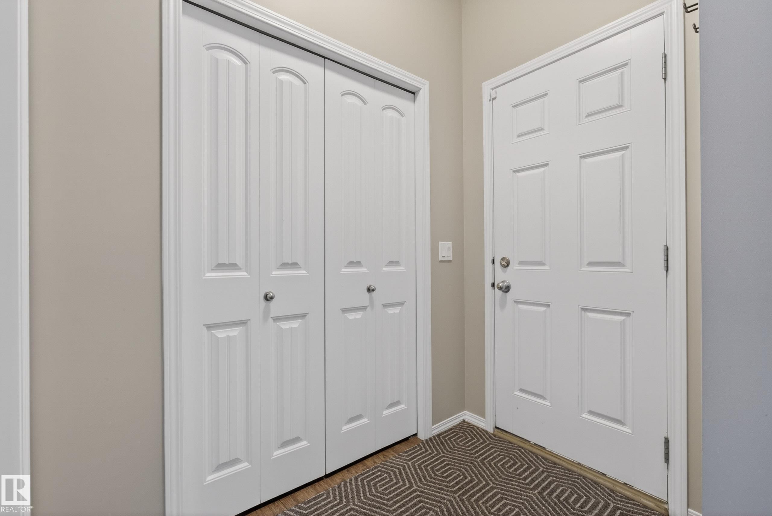 Back entryway featuring a paneled door, bi-fold closet doors, and light-toned wall paint - 2325 69A Street, Edmonton, AB