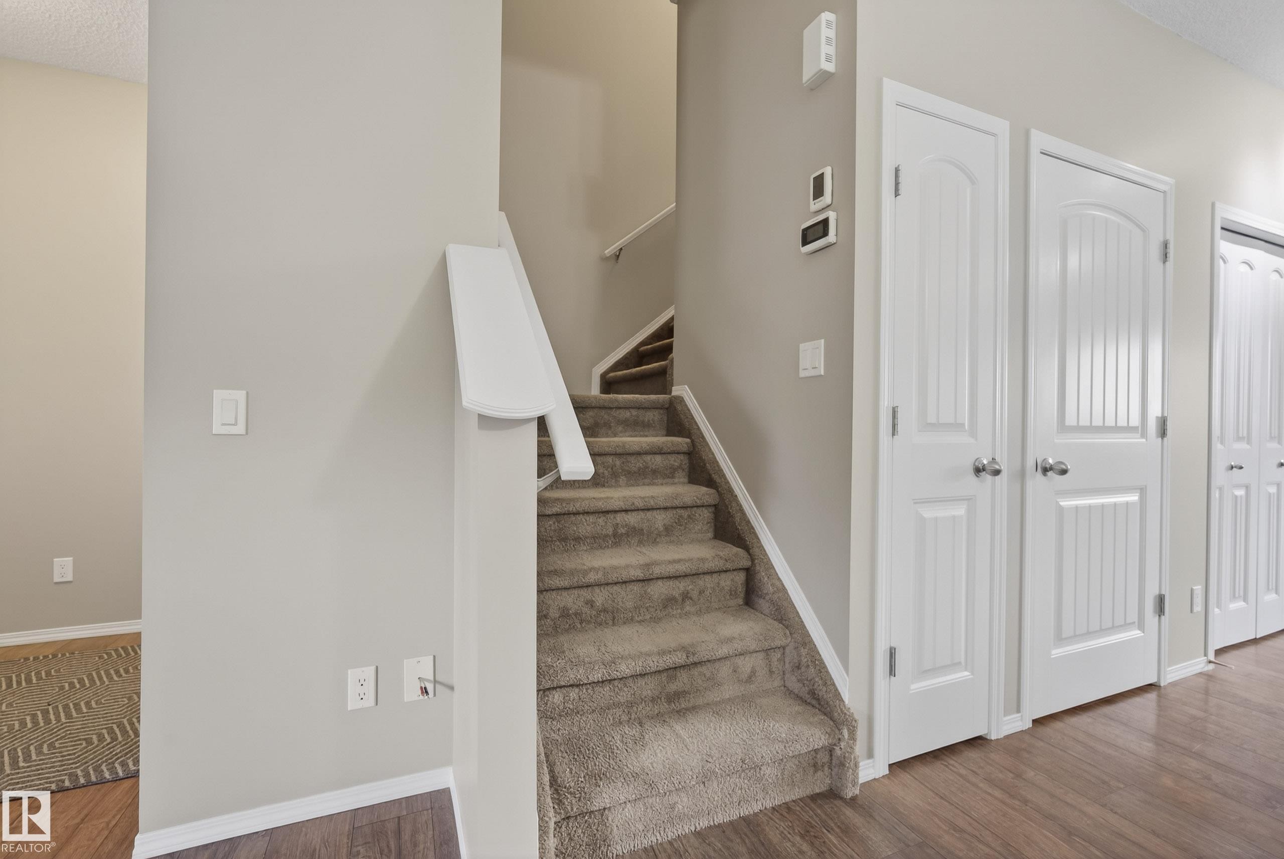 Carpeted staircase with white handrail and wood-finish flooring - 2325 69A Street, Edmonton, AB