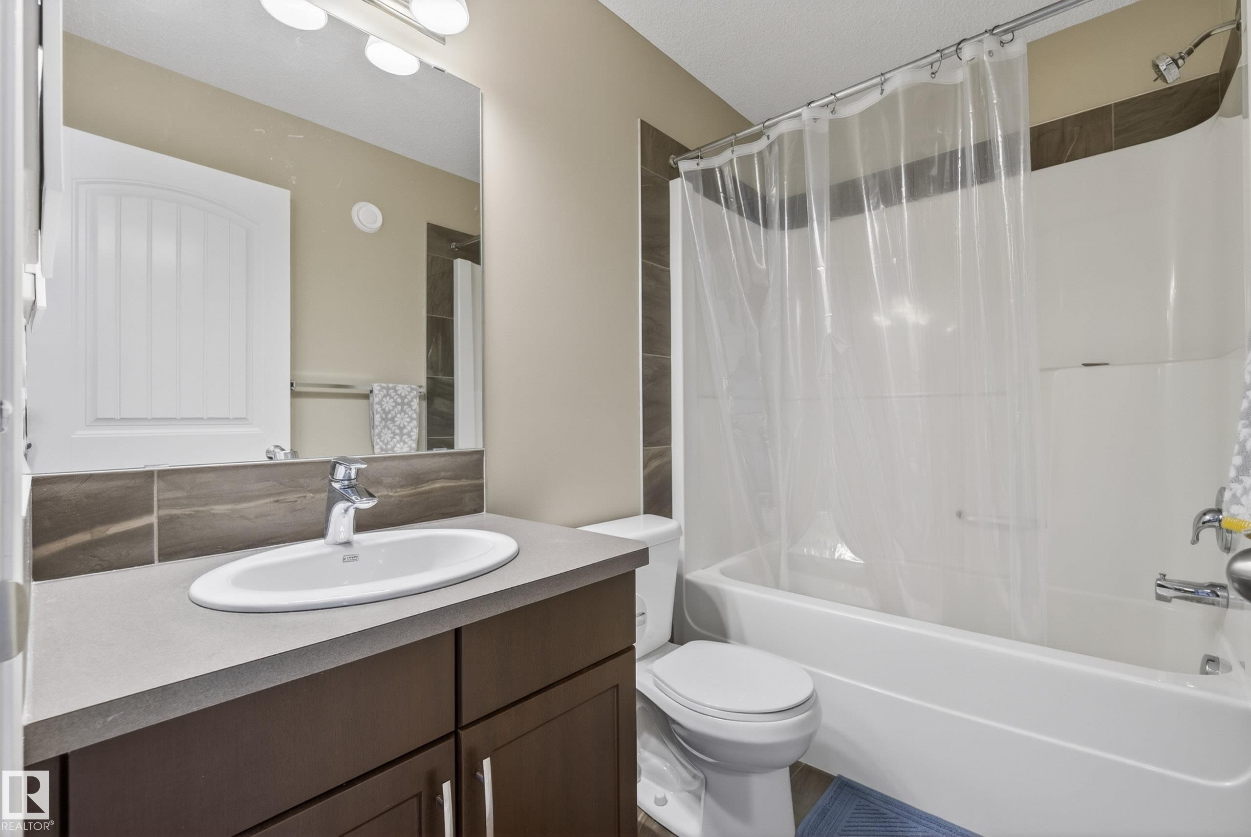 Bathroom featuring a large vanity with an oval undermount sink, dark wood cabinetry, and a spacious mirror - 2325 69A Street, Edmonton, AB