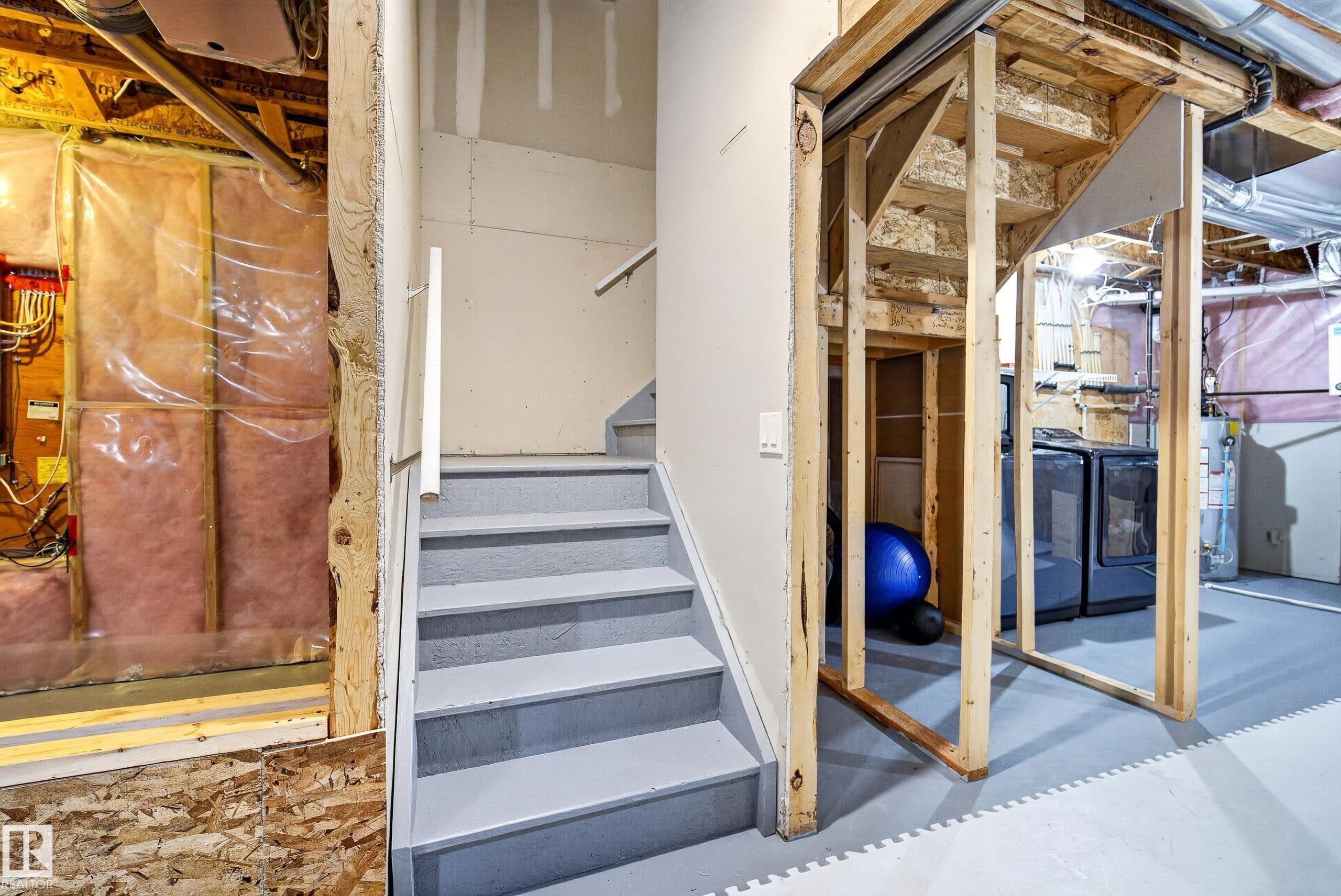 Unfinished basement area featuring a utility staircase, exposed framing, and insulated wall sections - 2325 69A Street, Edmonton, AB