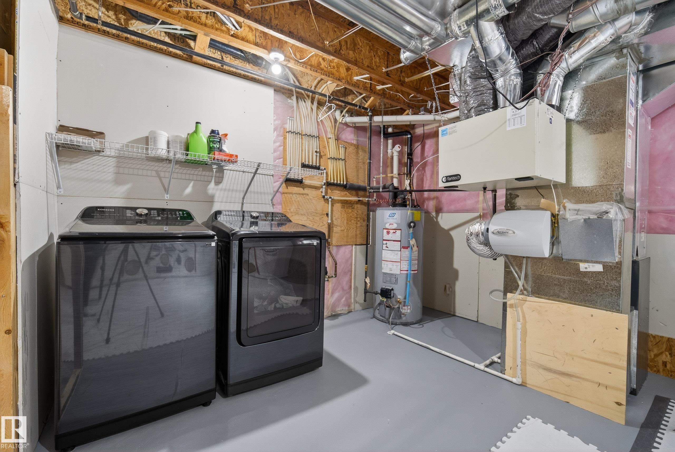Dedicated laundry area featuring modern appliances, wire shelving, and a water heater - 2325 69A Street, Edmonton, AB