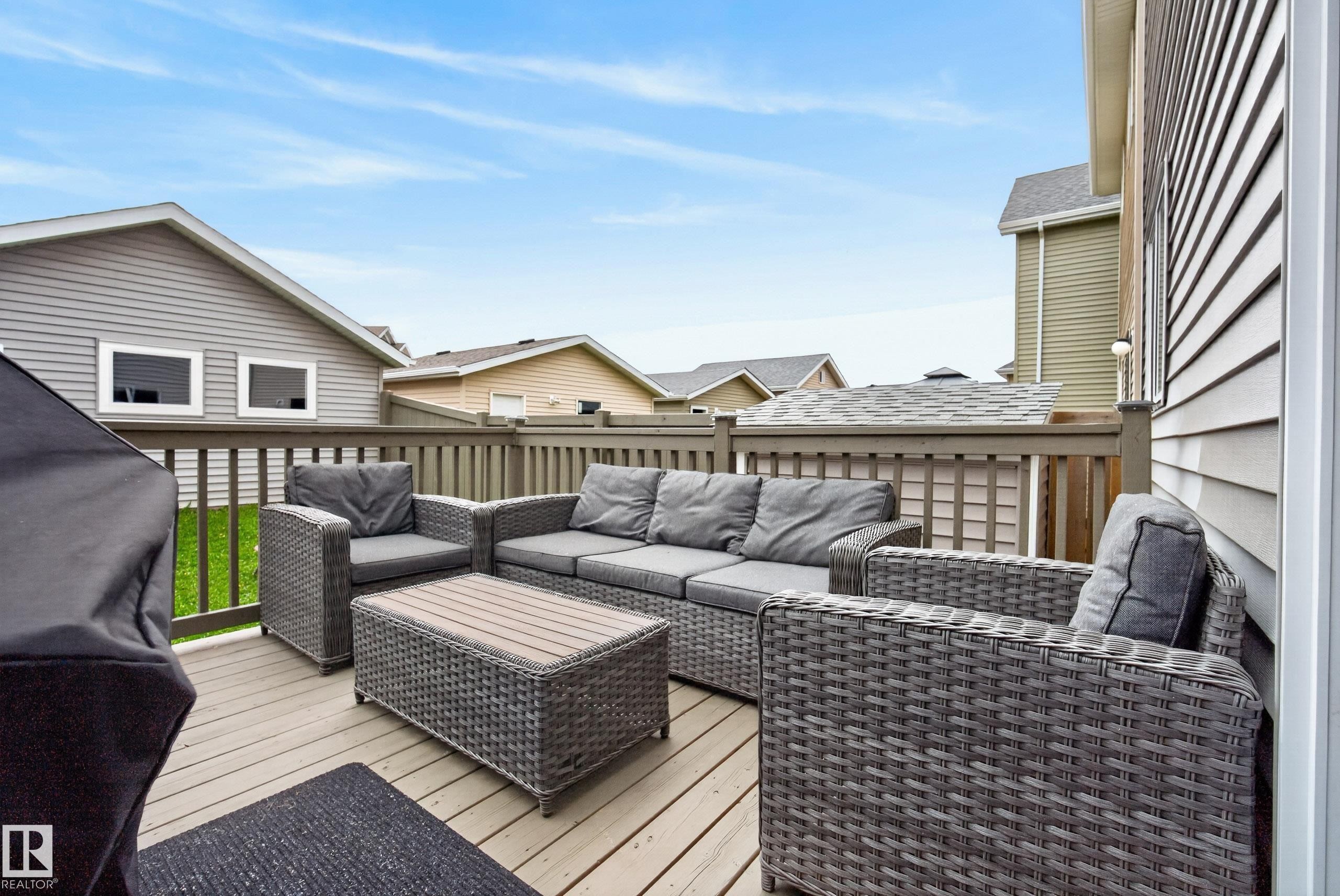 Outdoor deck featuring composite decking, wood railing, and vinyl siding - 2325 69A Street, Edmonton, AB
