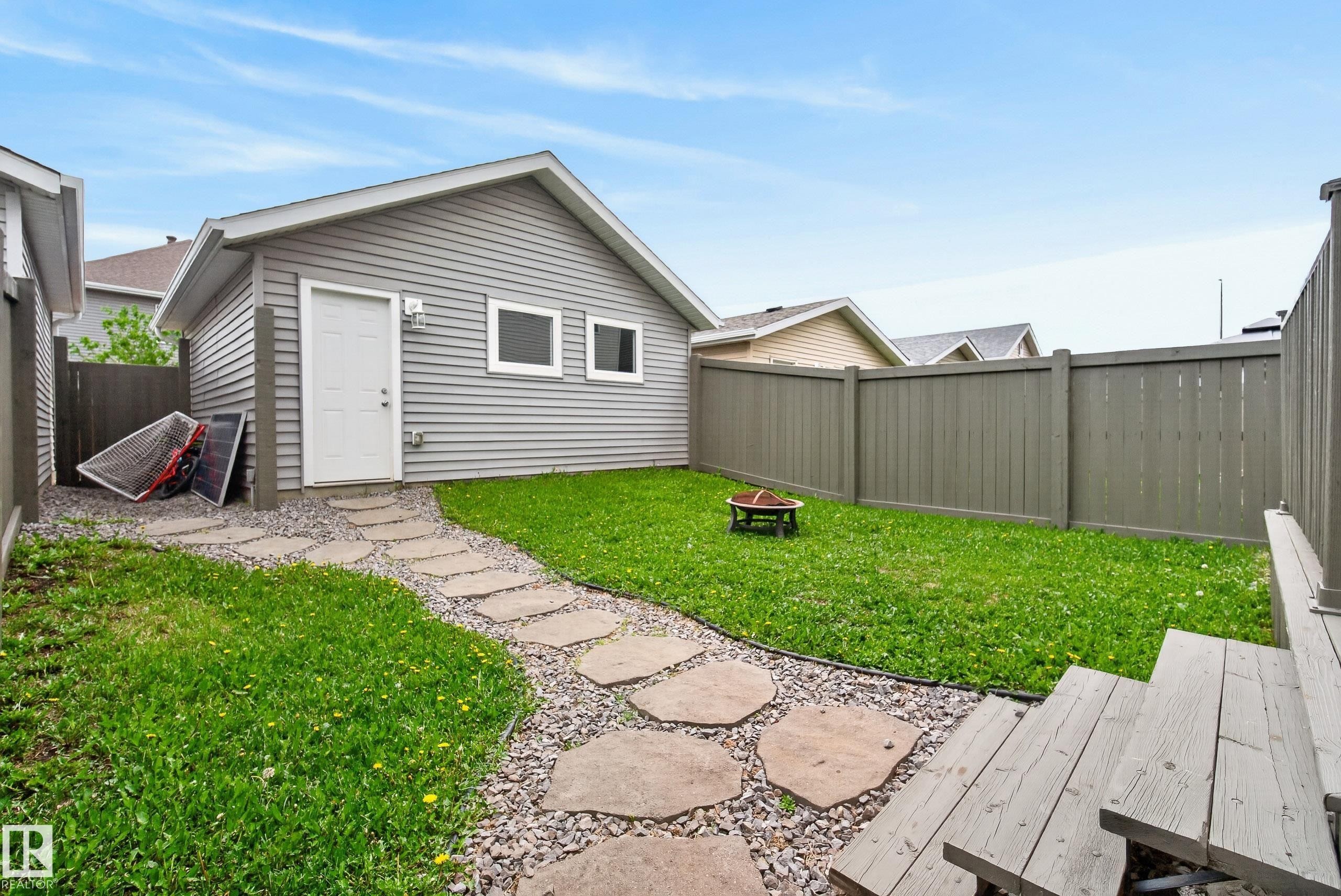 Detached outbuilding with light grey siding, white door, and two rectangular windows - 2325 69A Street, Edmonton, AB