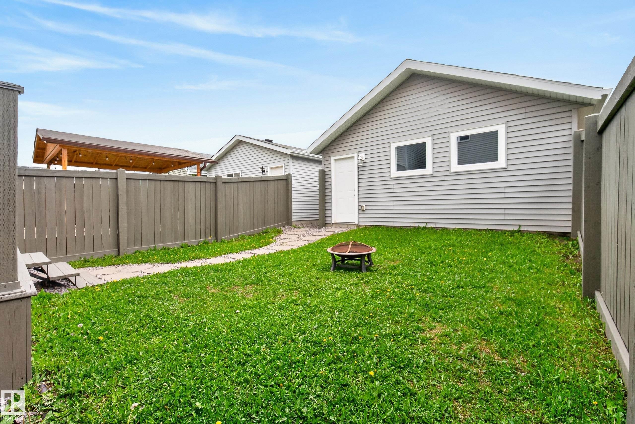 Expansive backyard featuring a lush lawn, privacy fencing, and a detached structure with siding - 2325 69A Street, Edmonton, AB