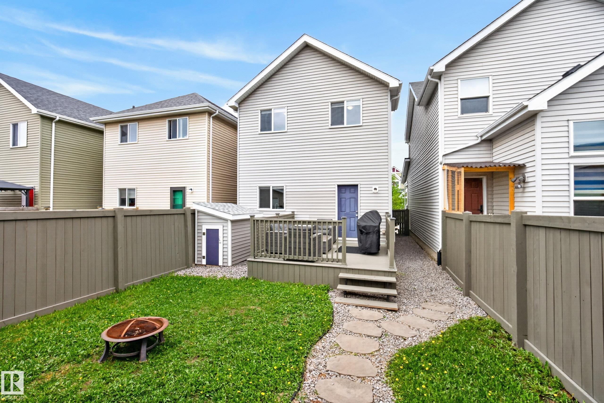 Fenced backyard featuring a wood deck, stone pathway, and a small utility shed - 2325 69A Street, Edmonton, AB