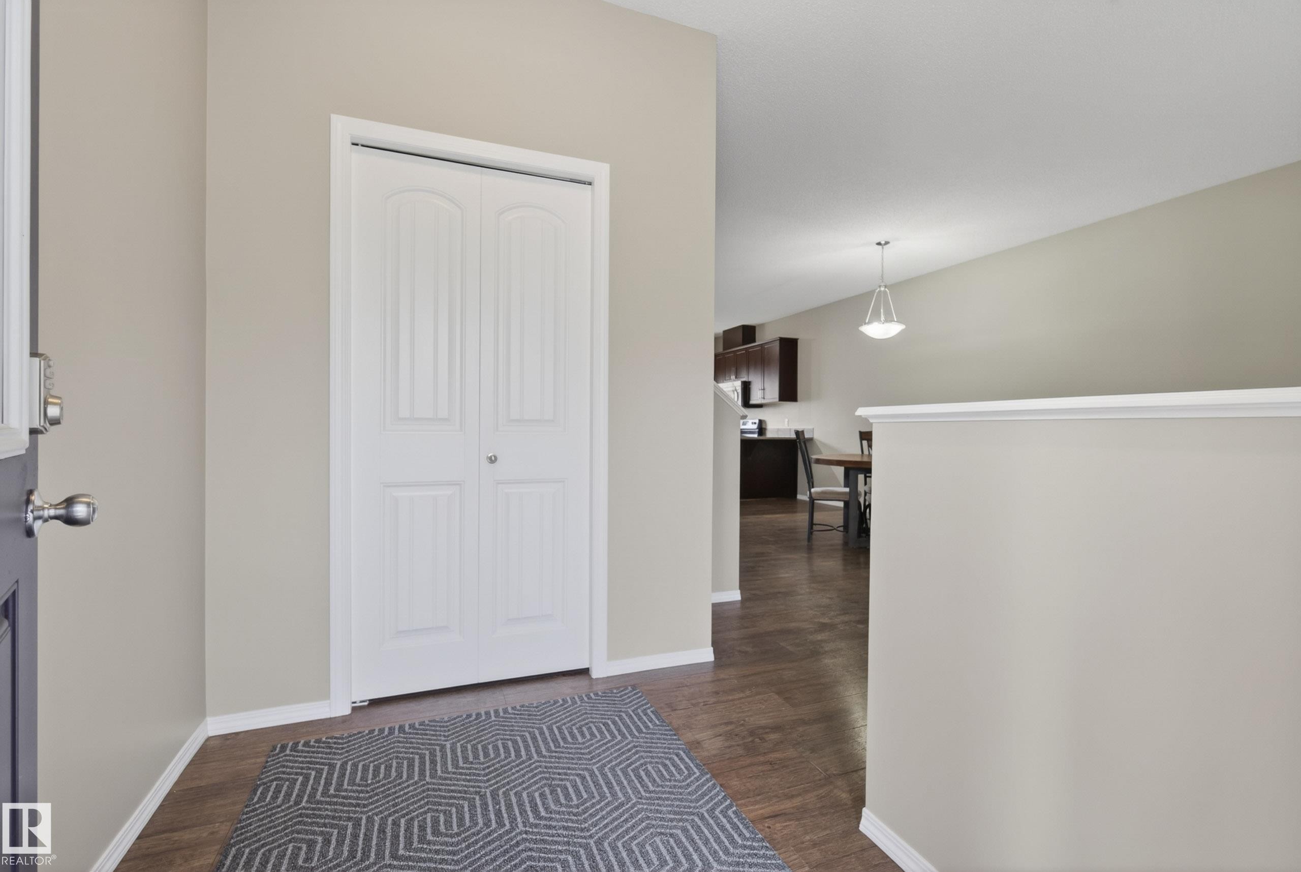 Entryway featuring wood-finish flooring, a white bi-fold closet, and neutral painted walls - 2325 69A Street, Edmonton, AB