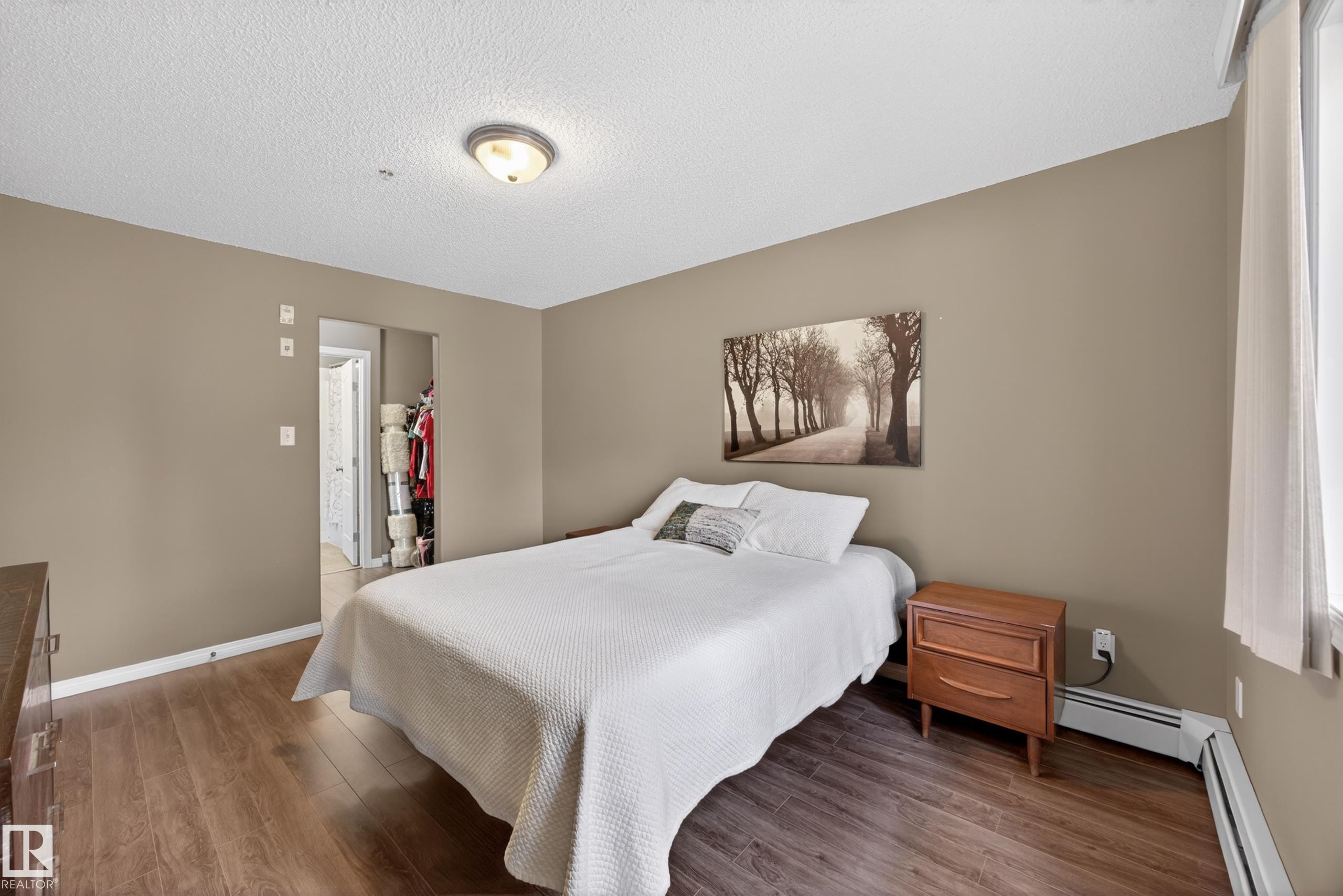 Bedroom featuring wood-finish flooring, neutral wall paint, and a textured ceiling - 111 3425 19, Edmonton, AB