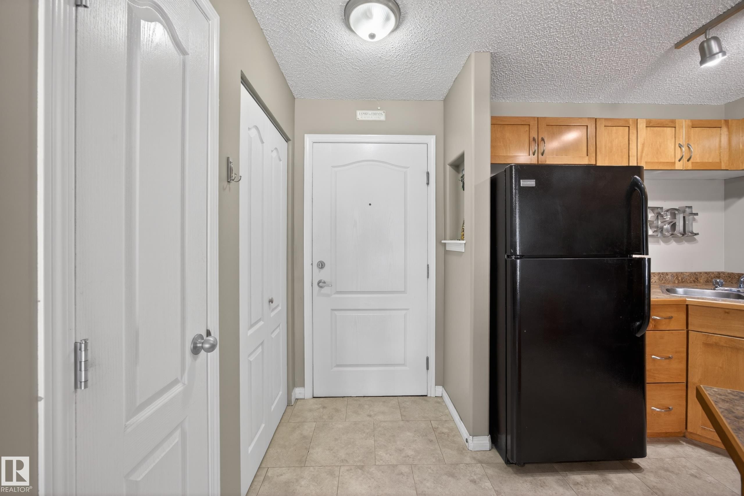 Entryway featuring light-toned flooring, white paneled doors, and an overhead flush-mount light fixture - 111 3425 19, Edmonton, AB