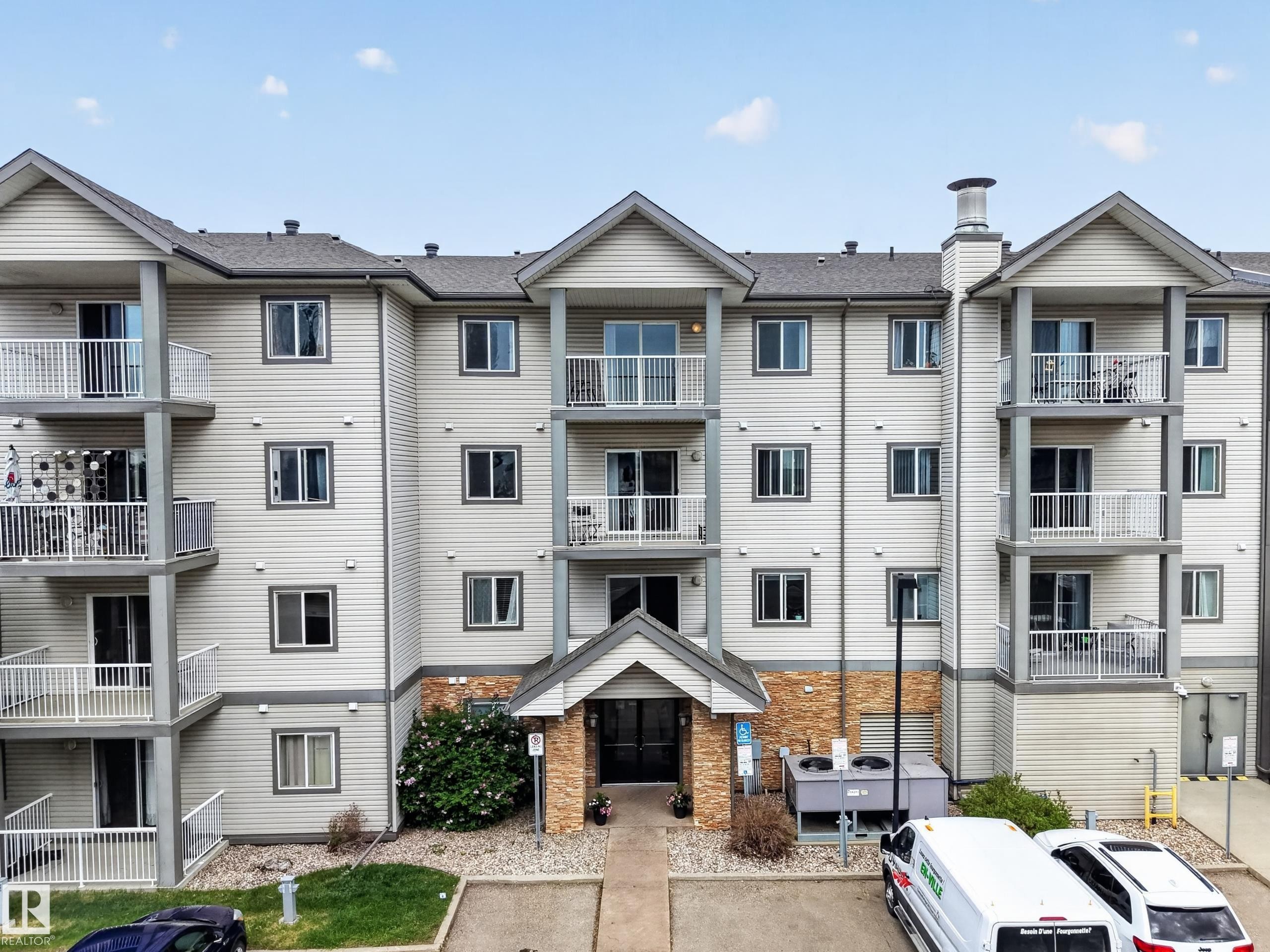 Multi-story residential building featuring light-colored siding and a contrasting gray roof - 111 3425 19, Edmonton, AB