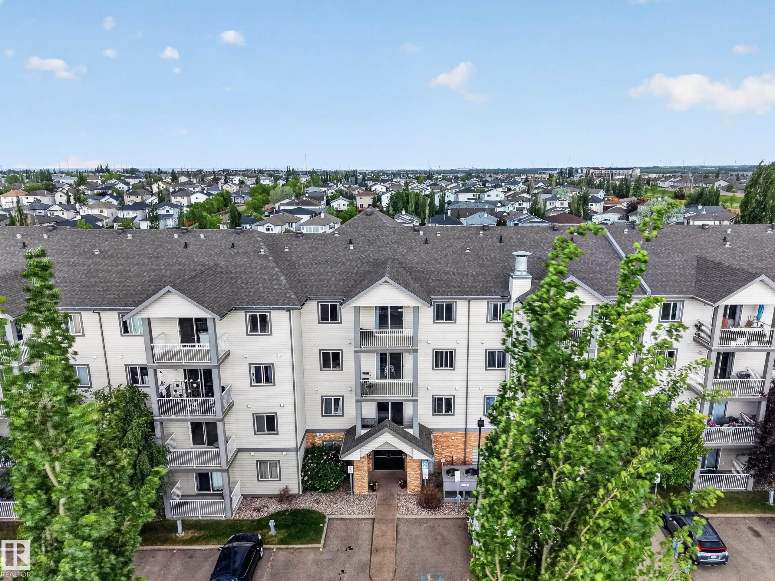 Multi-story residential building with light-colored siding and dark shingle roofing - 111 3425 19, Edmonton, AB