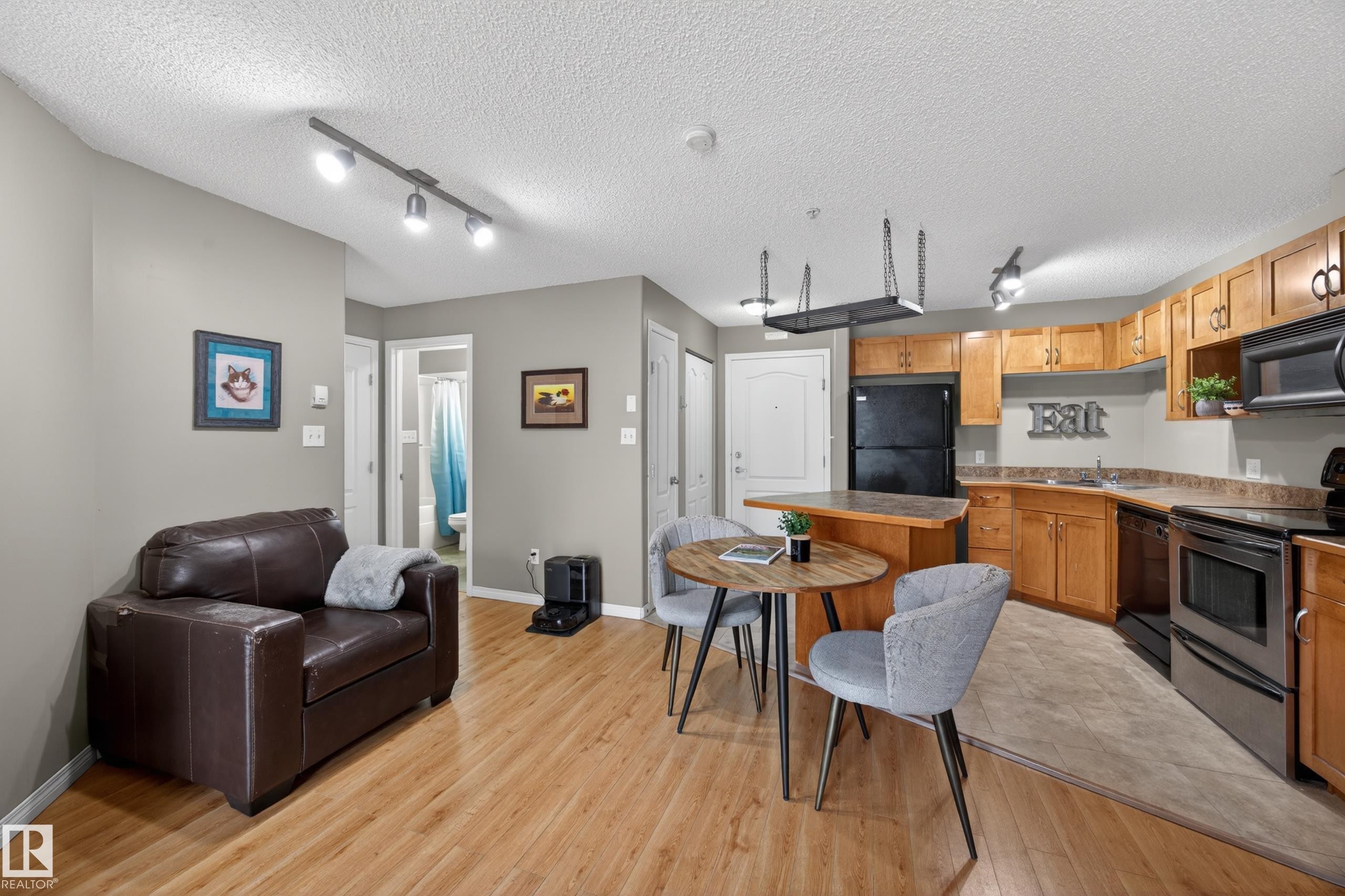 Open-concept living area featuring wood-finish flooring extending into the kitchen - 111 3425 19, Edmonton, AB