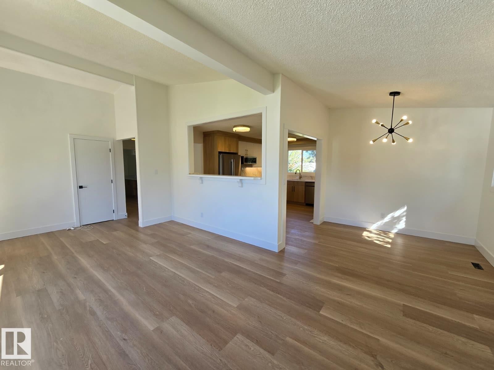 Open concept living space featuring wood-finish flooring and a contemporary chandelier - 18526 86A Avenue, Edmonton, AB - Indoor