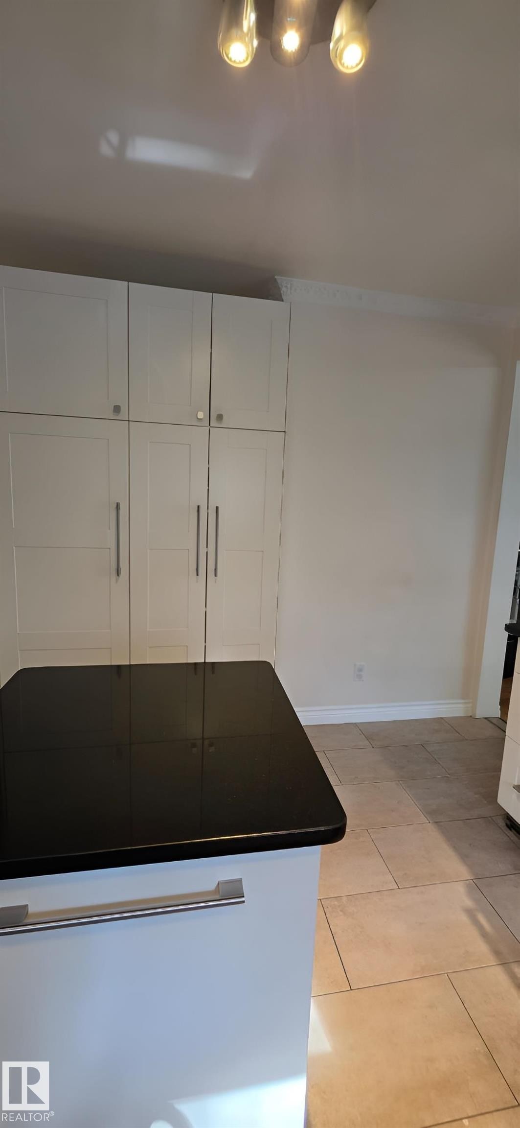 Kitchen island with a black countertop and a white base featuring an integrated handle - 6704 93 Street, Edmonton, AB