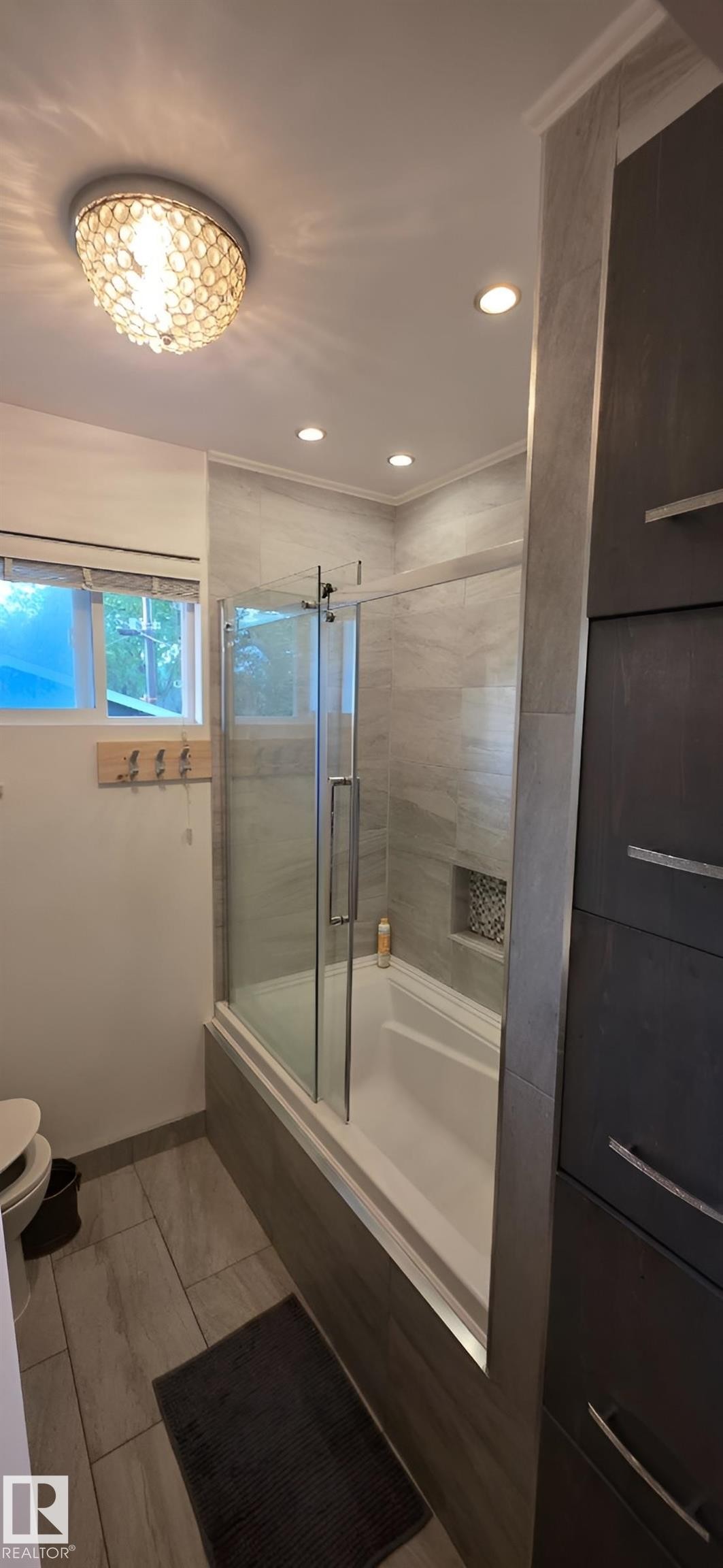 Full bathroom featuring a tub-shower combination with glass enclosure, tiled surround, and integrated niche - 6704 93 Street, Edmonton, AB