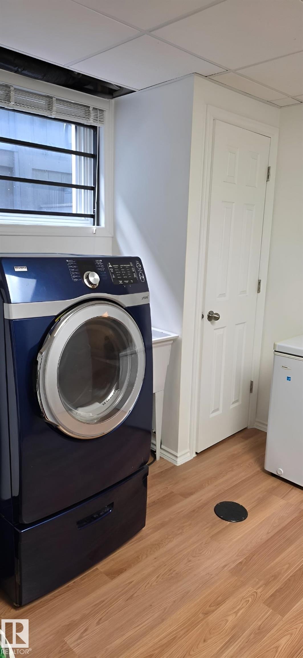 Dedicated laundry area featuring wood-finish flooring and a utility sink - 6704 93 Street, Edmonton, AB