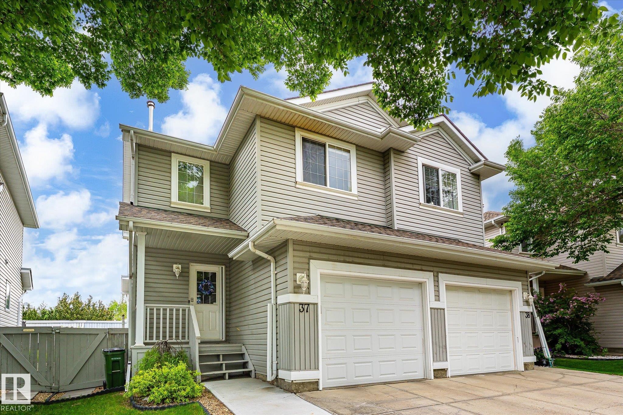 Two-story residence featuring light gray siding, white trim, and a two-car garage - #37 4020 21 St Nw, Edmonton, AB - Outdoor