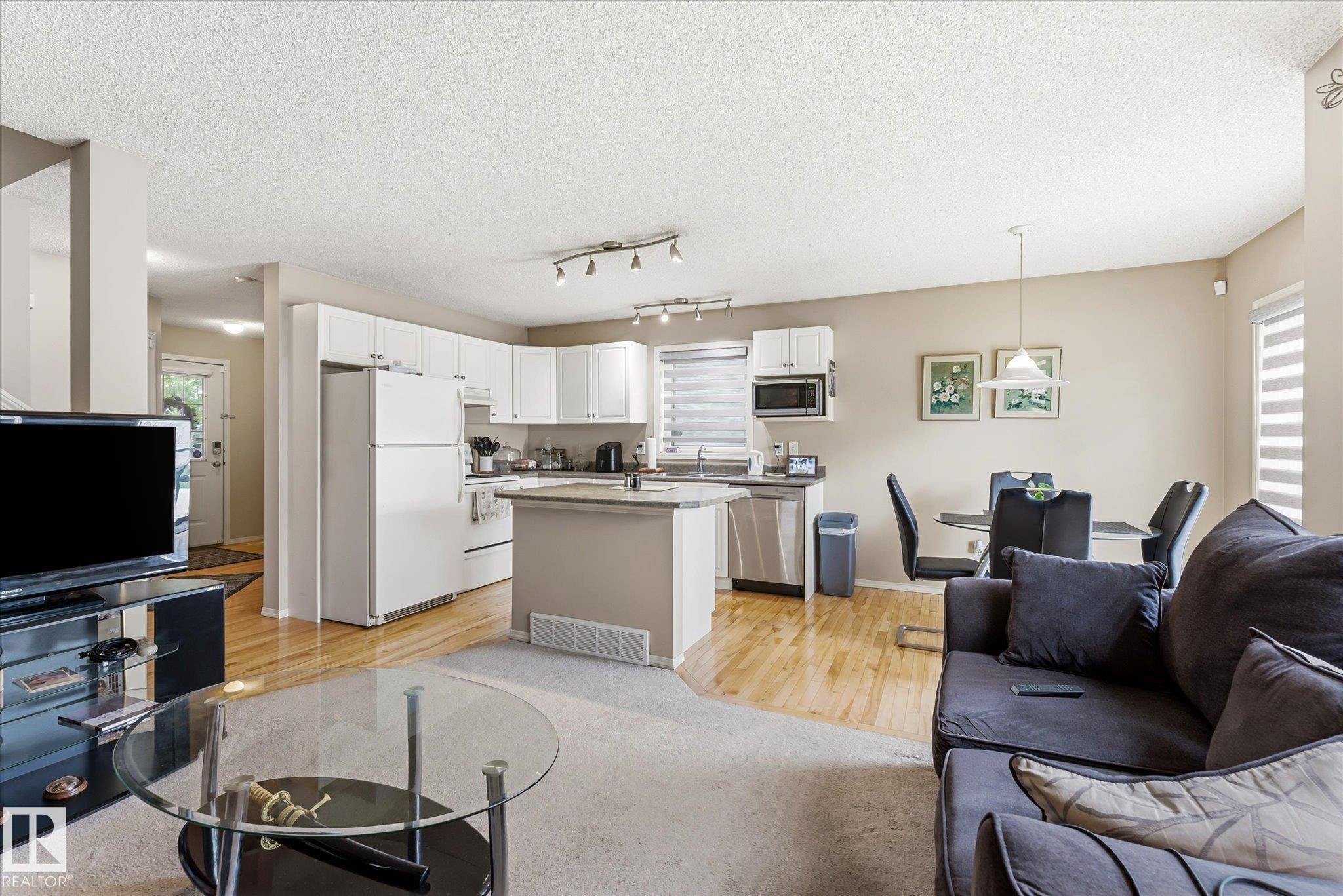 Open-concept living area with wood-finish flooring extending into the kitchen and dining areas - #37 4020 21 St Nw, Edmonton, AB - Indoor