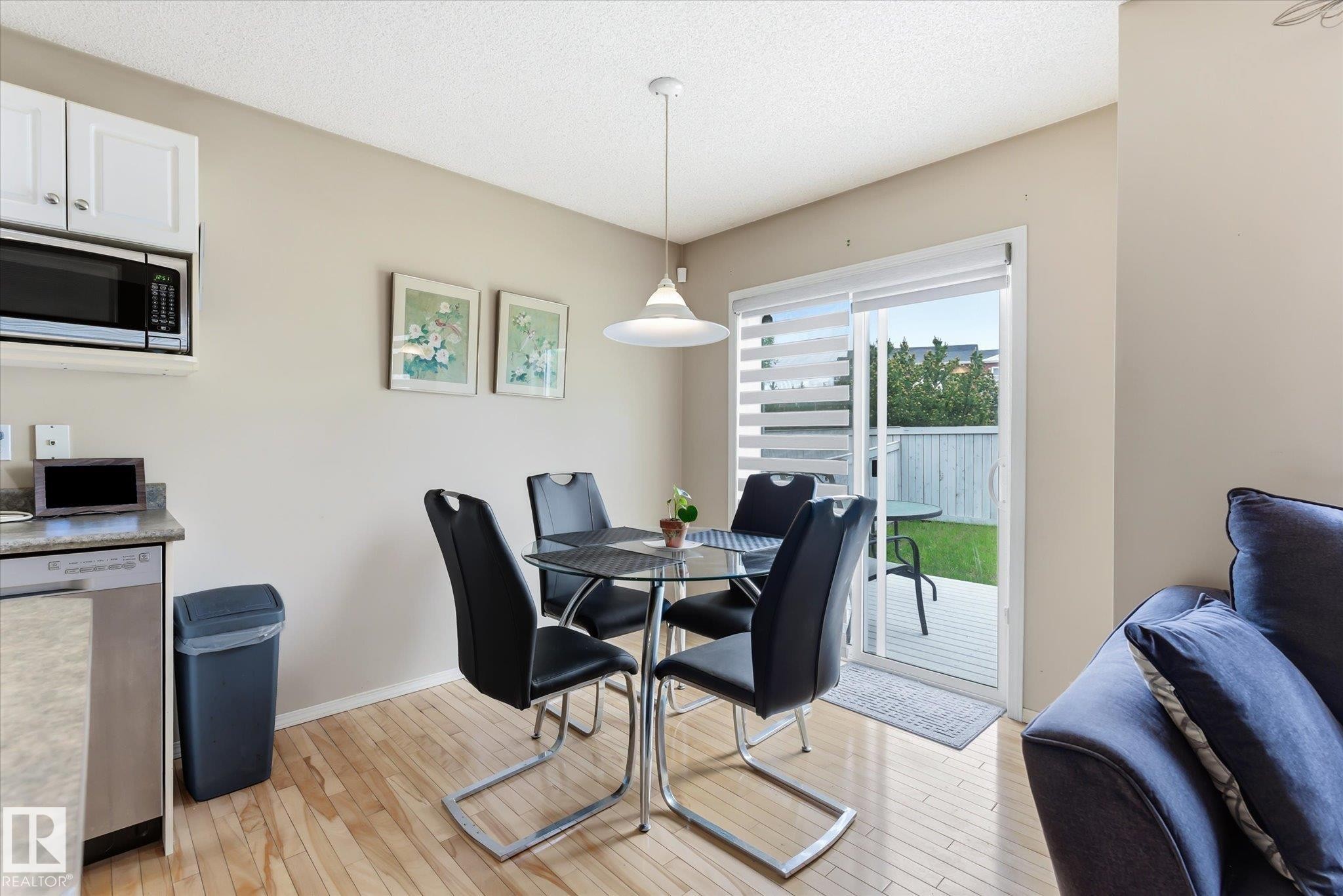 Dining area with wood-finish flooring and a contemporary pendant light fixture - #37 4020 21 St Nw, Edmonton, AB - Indoor Photo Showing Dining Room