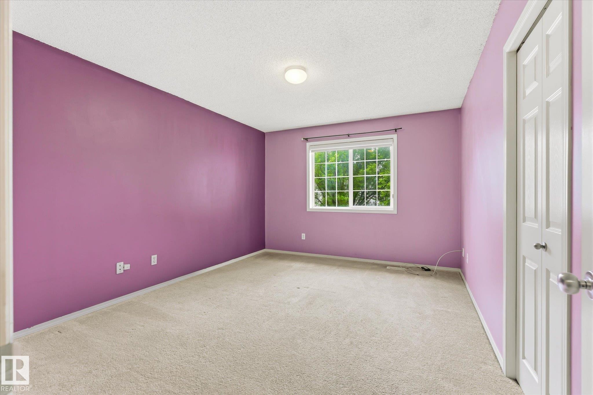 Room featuring a large window, neutral carpet, ceiling light fixture, and white bi-fold closet doors - #37 4020 21 St Nw, Edmonton, AB - Indoor Photo Showing Other Room