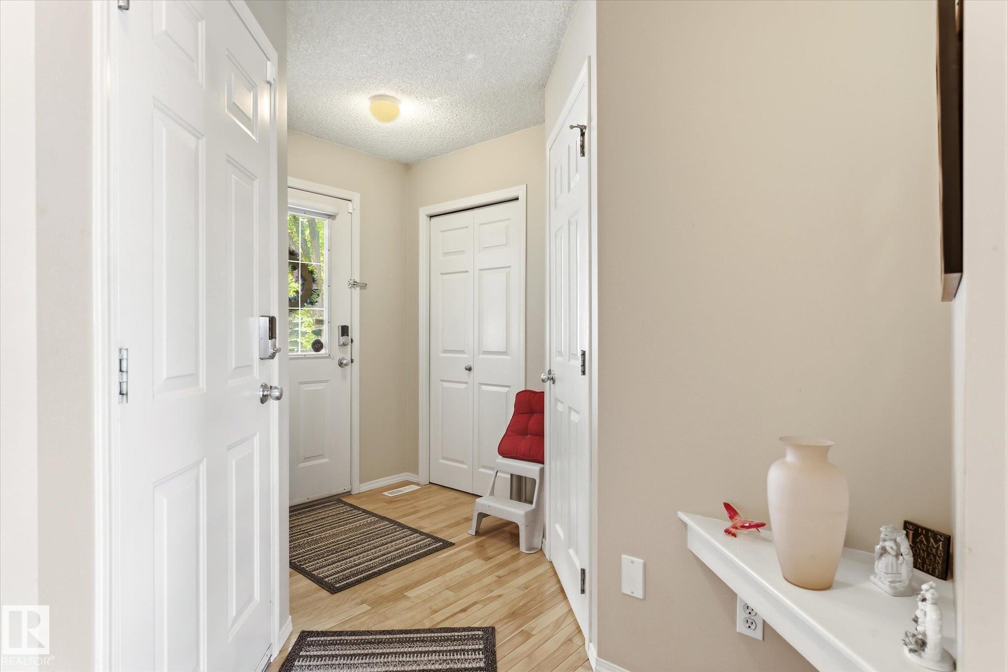 Front entry foyer with wood-finish flooring, light tan walls, and white trim - #37 4020 21 St Nw, Edmonton, AB - Indoor Photo Showing Other Room