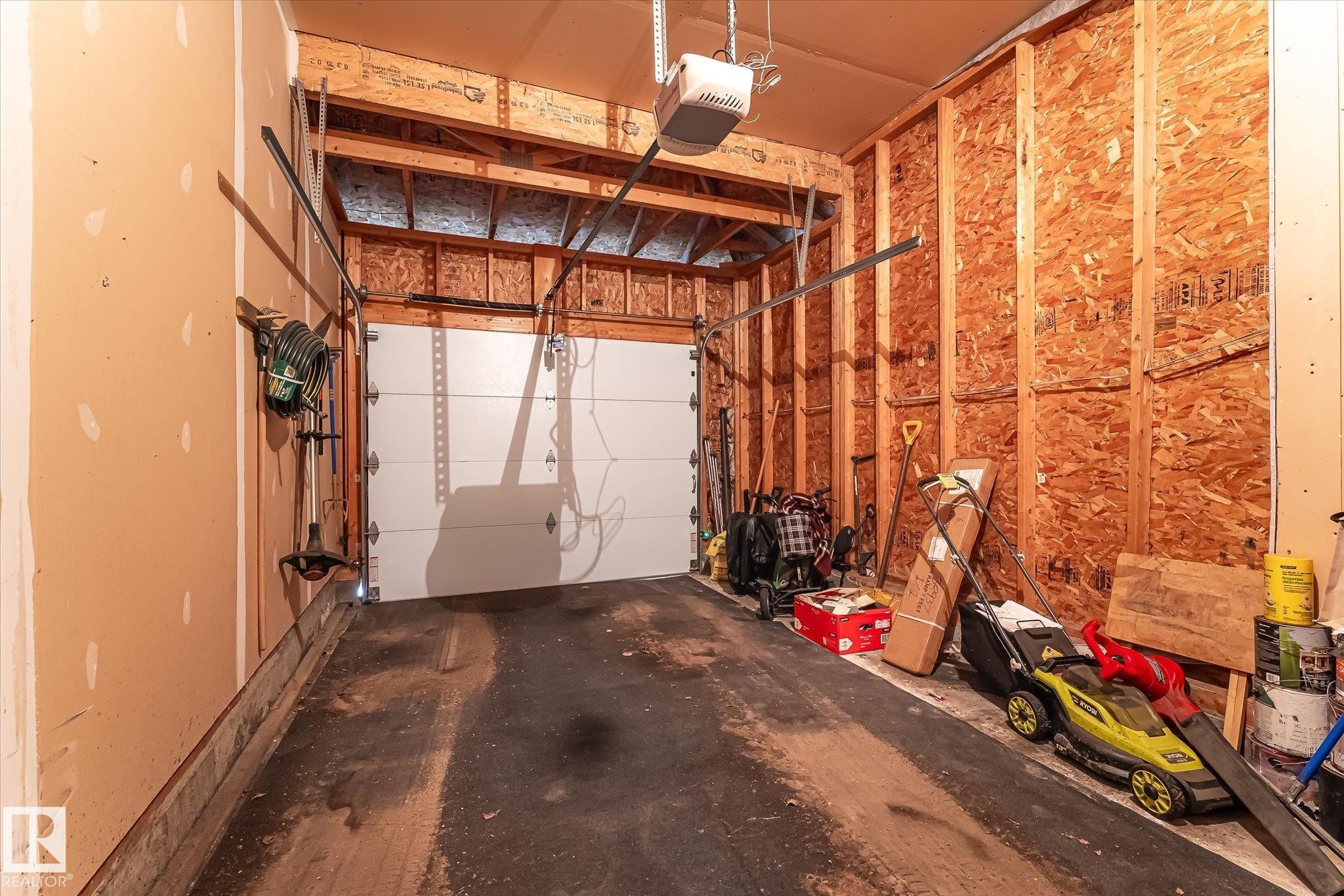 Interior garage with a white overhead door and an automatic opener - #37 4020 21 St Nw, Edmonton, AB - Indoor Photo Showing Garage