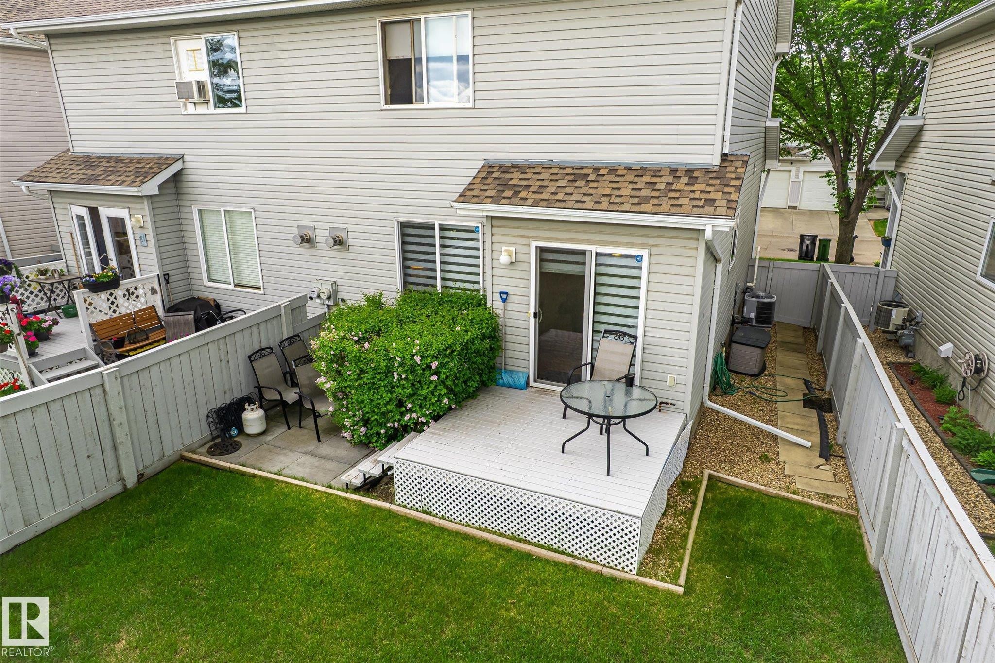 Fenced backyard featuring a manicured lawn, a private deck, and mature landscaping - #37 4020 21 St Nw, Edmonton, AB - Outdoor With Exterior