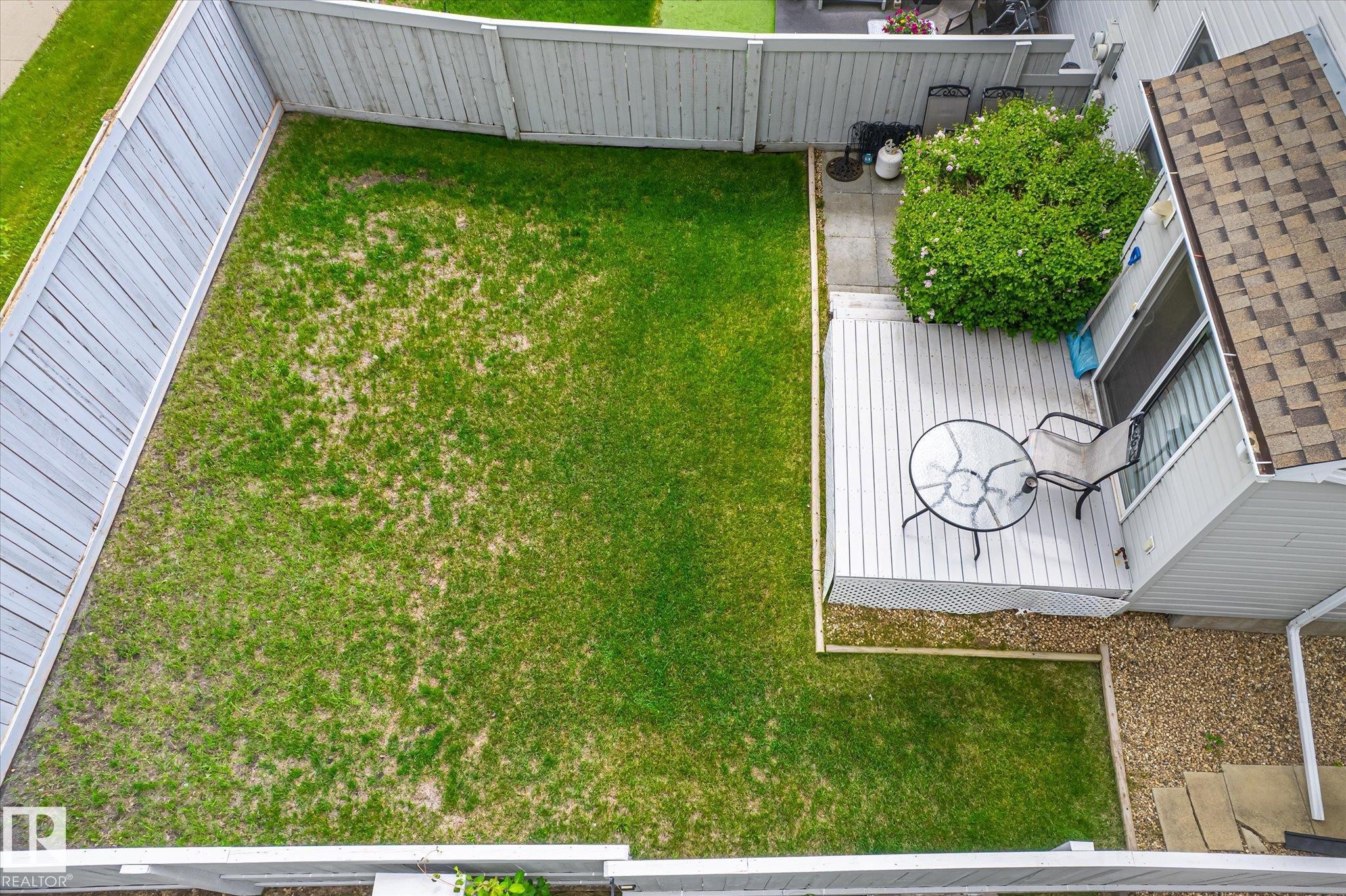 Private backyard featuring a wooden privacy fence, a spacious deck, and a patio area - #37 4020 21 St Nw, Edmonton, AB - Outdoor