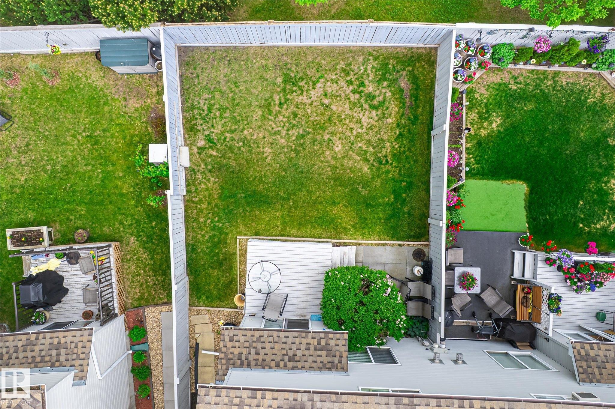 Private fenced yard featuring a spacious green lawn and an attached deck - #37 4020 21 St Nw, Edmonton, AB - Outdoor