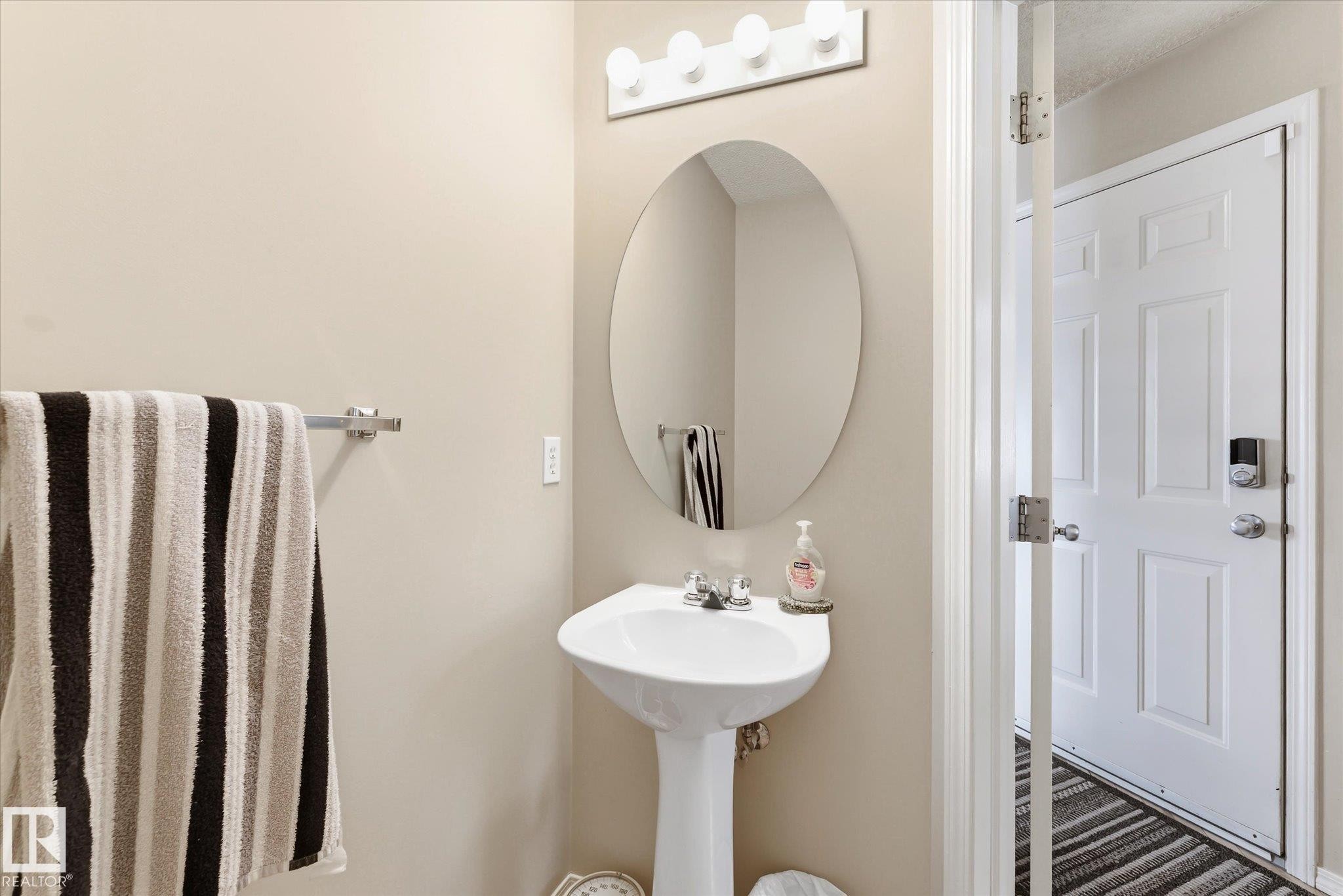 Pedestal sink with chrome-finish faucet, illuminated by a multi-bulb vanity light fixture - #37 4020 21 St Nw, Edmonton, AB - Indoor Photo Showing Bathroom