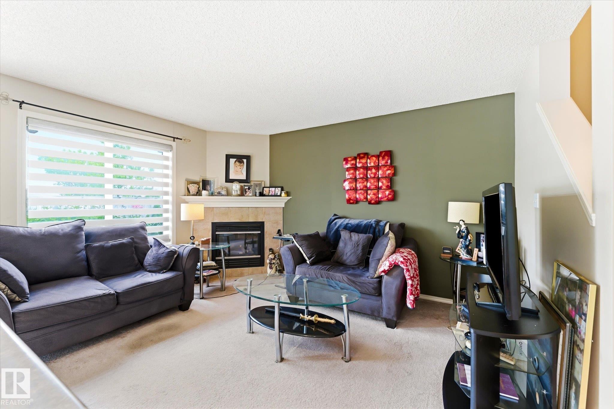 Living area featuring a corner fireplace with a tiled surround and mantel - #37 4020 21 St Nw, Edmonton, AB - Indoor Photo Showing Living Room With Fireplace