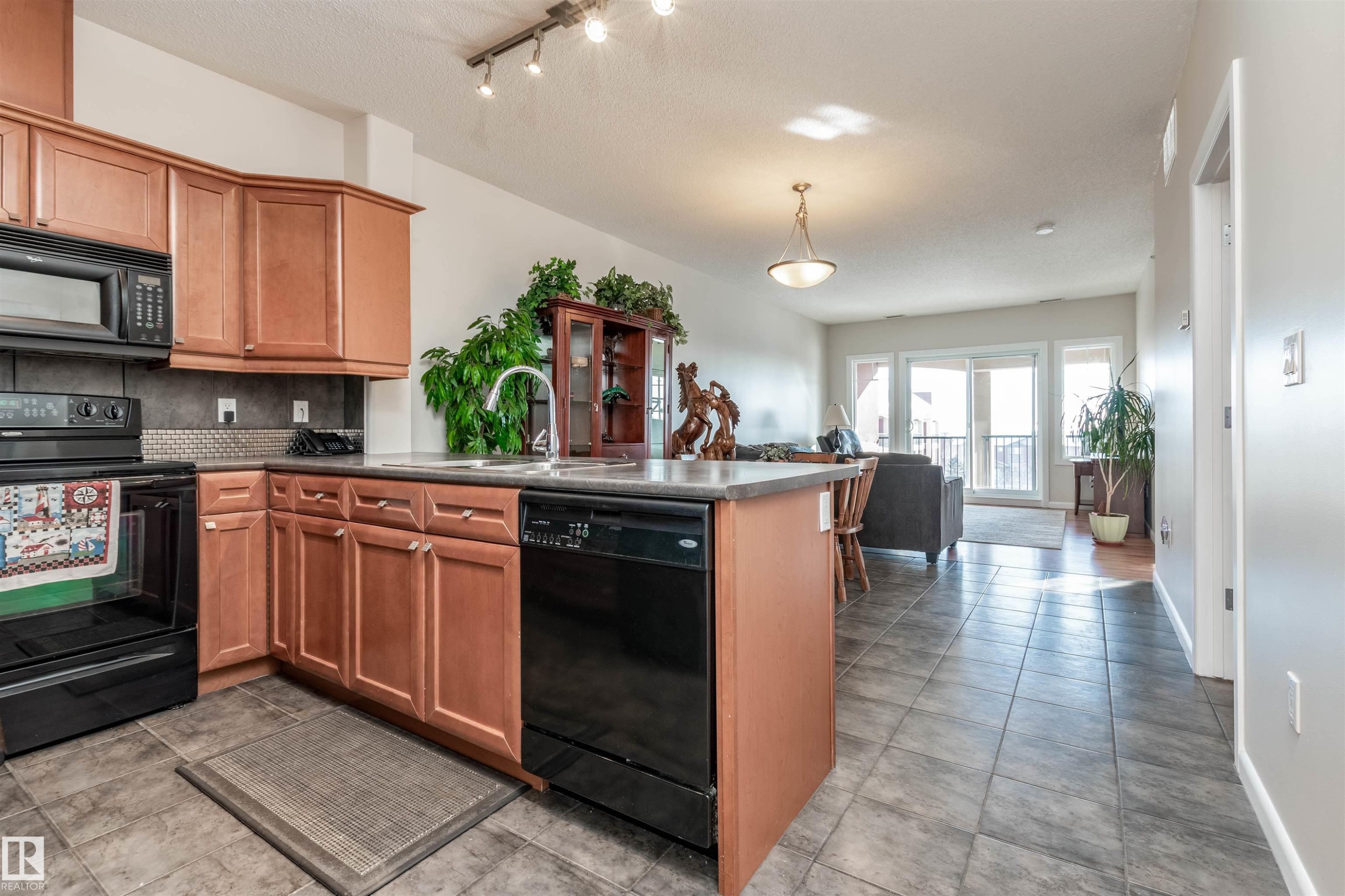Kitchen featuring light wood cabinetry, black appliances, a dark countertop, and a tiled backsplash - 439 300 Palisades Way, Sherwood Park, AB - Indoor Photo Showing Kitchen