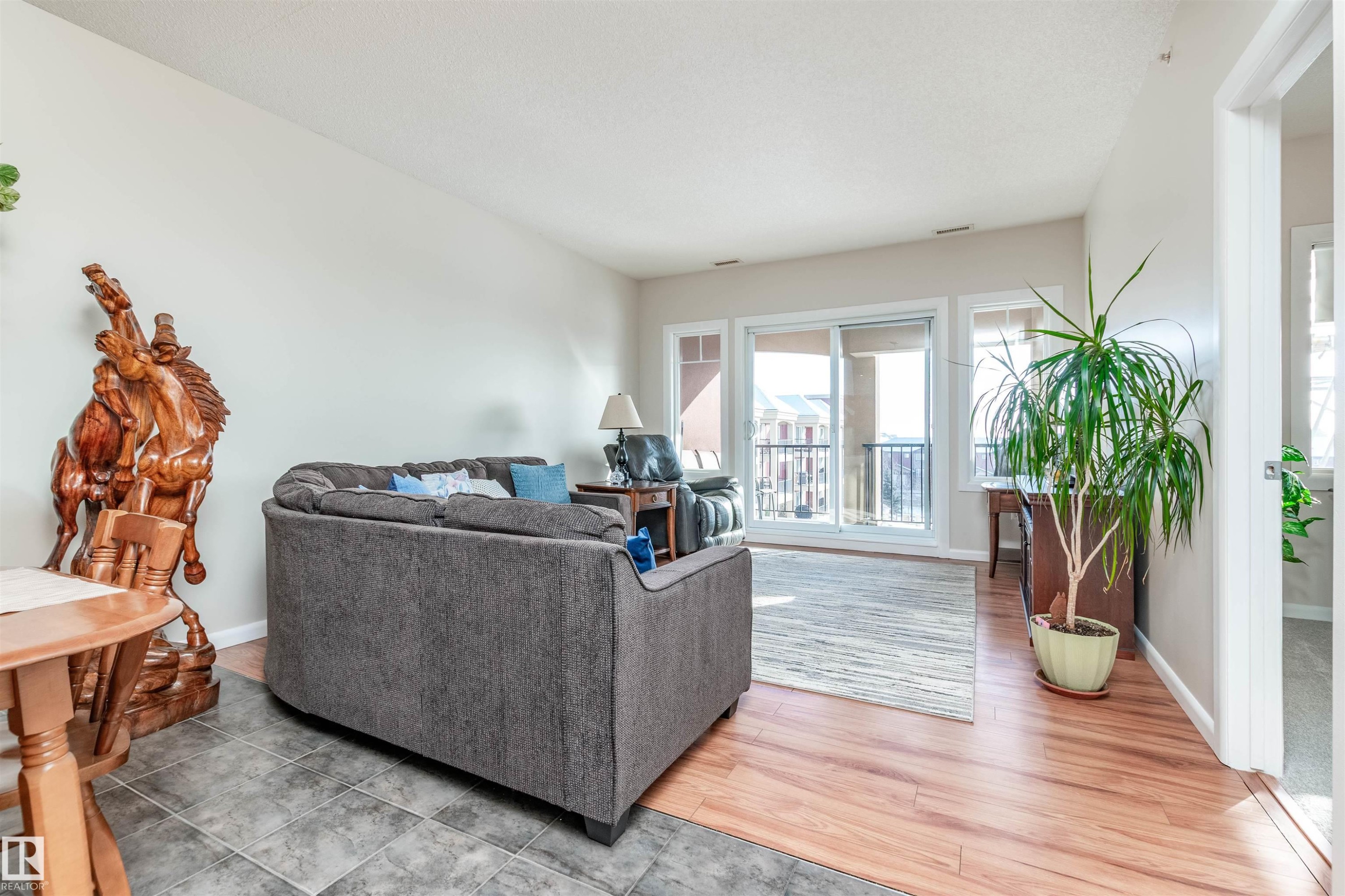Living area featuring a sliding glass door to an exterior balcony, wood-finish flooring, and a tiled entry - 439 300 Palisades Way, Sherwood Park, AB - Indoor Photo Showing Living Room