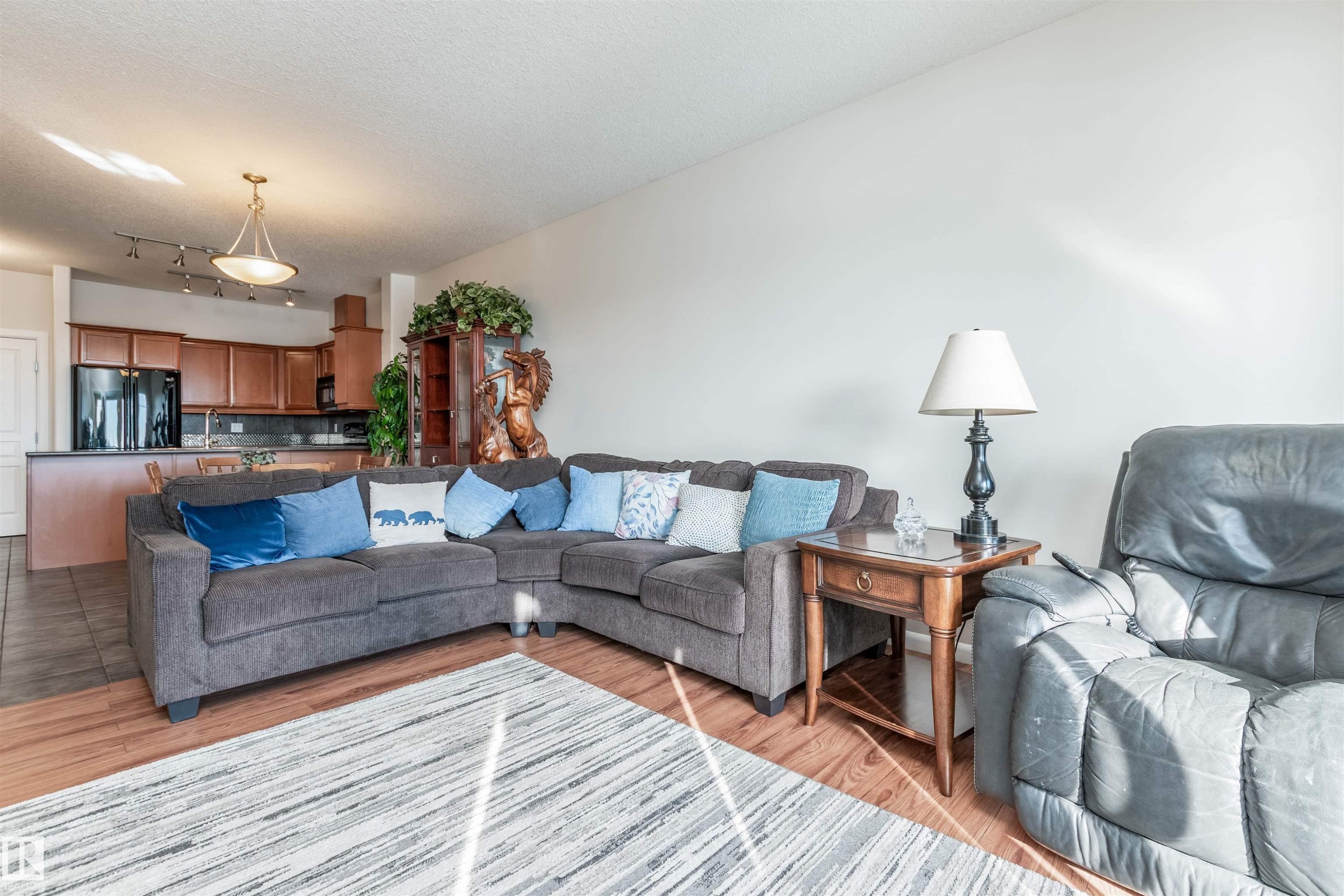 Open-concept living area featuring wood-finish flooring, a kitchen island, and a pendant light fixture - 439 300 Palisades Way, Sherwood Park, AB - Indoor Photo Showing Living Room