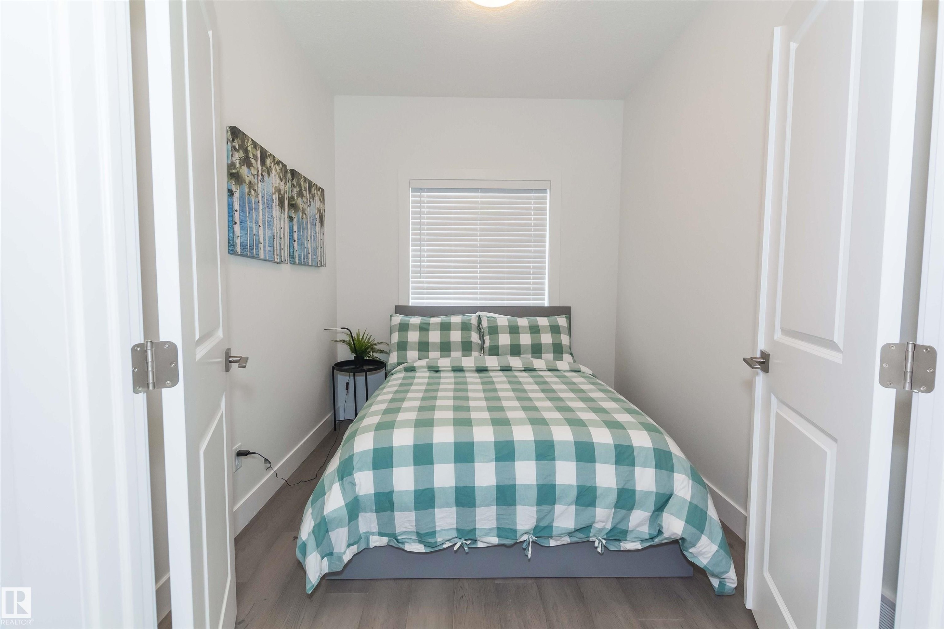 Bright interior space featuring a single window with horizontal blinds, recessed lighting, and wood-finish flooring - 15168 16 Street Nw, Edmonton, AB