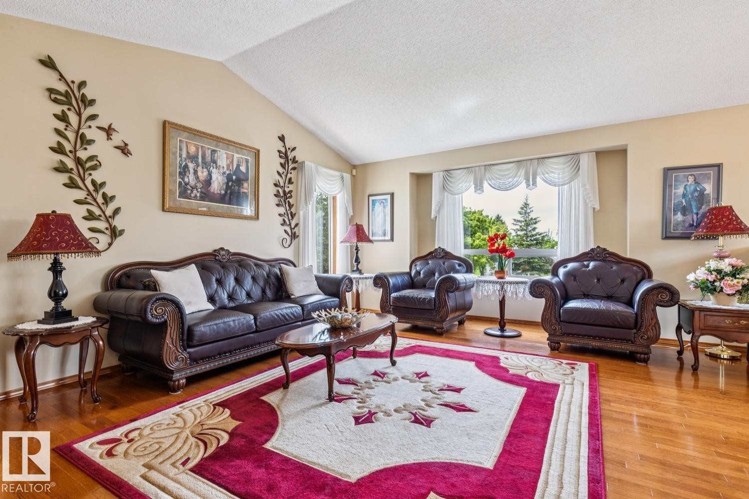 Living area featuring wood-finish flooring, a vaulted ceiling, a large bay window, and neutral wall tones - 5131 152A Avenue, Edmonton, AB
