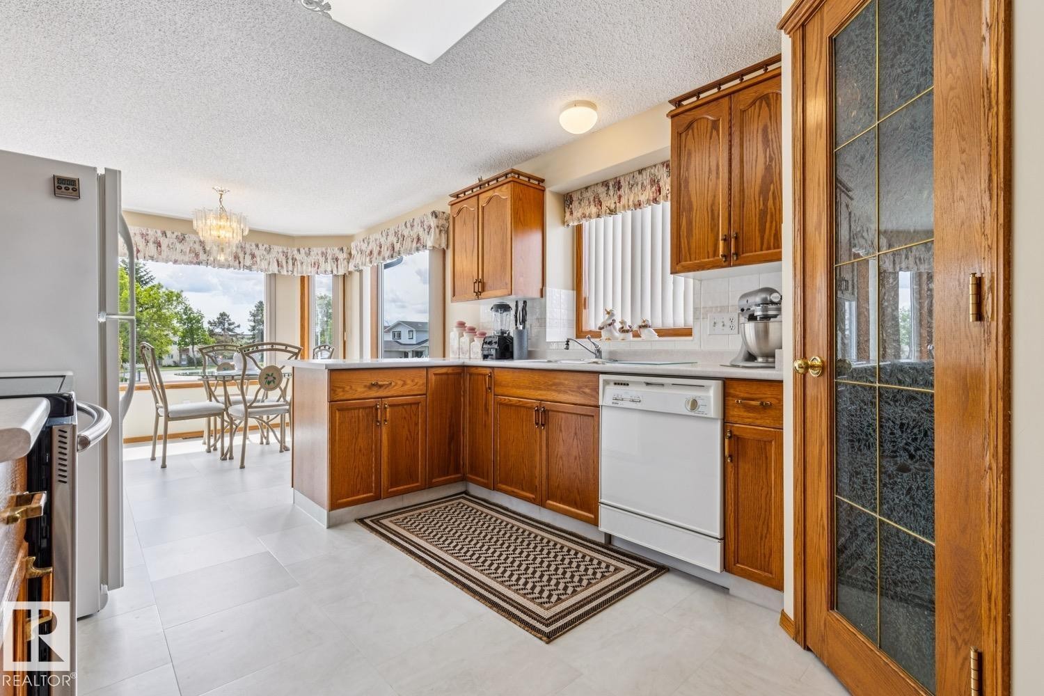 Kitchen area featuring wood cabinetry, white countertops, a bay window dining nook, and a new flooring - 5131 152A Avenue, Edmonton, AB