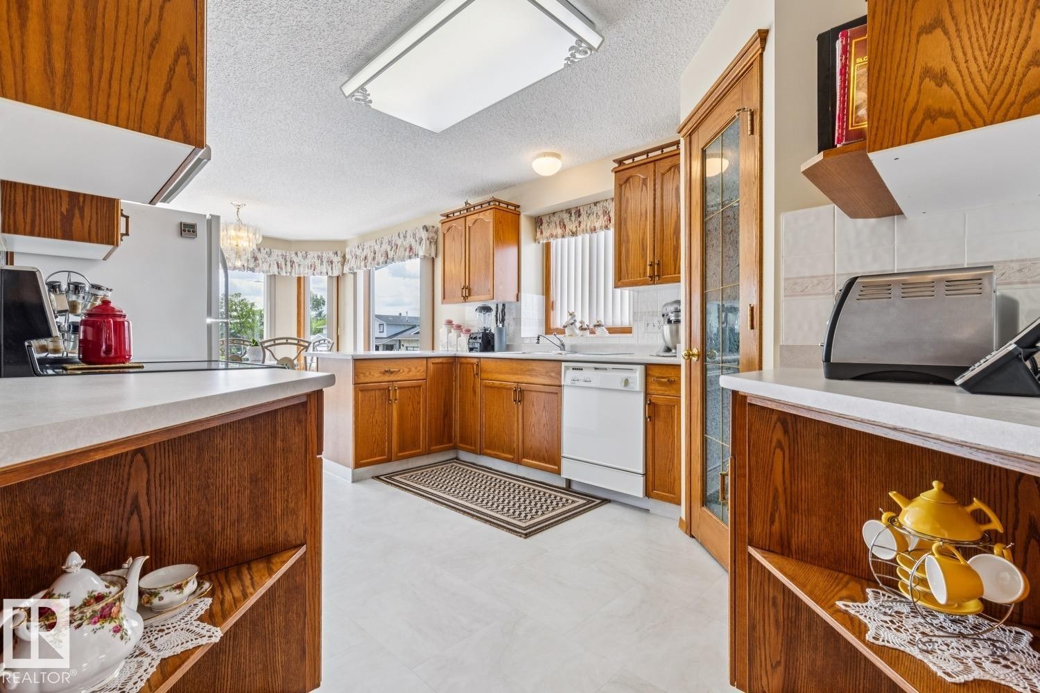 Kitchen featuring wood cabinetry, white countertops, a white dishwasher, and a bay window - 5131 152A Avenue, Edmonton, AB