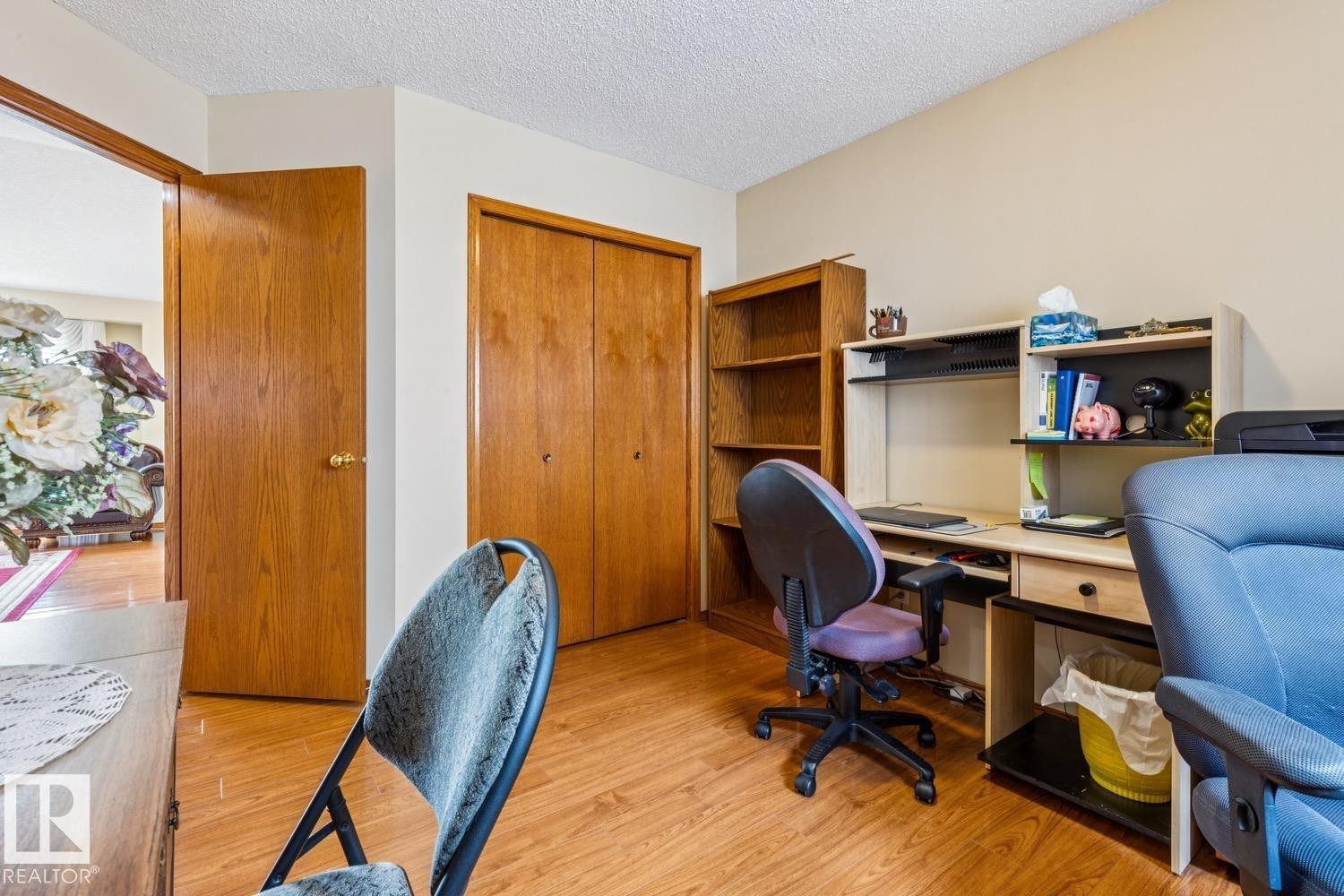 Versatile room with wood-finish flooring, neutral wall paint, and a built-in closet with bi-fold doors - 5131 152A Avenue, Edmonton, AB