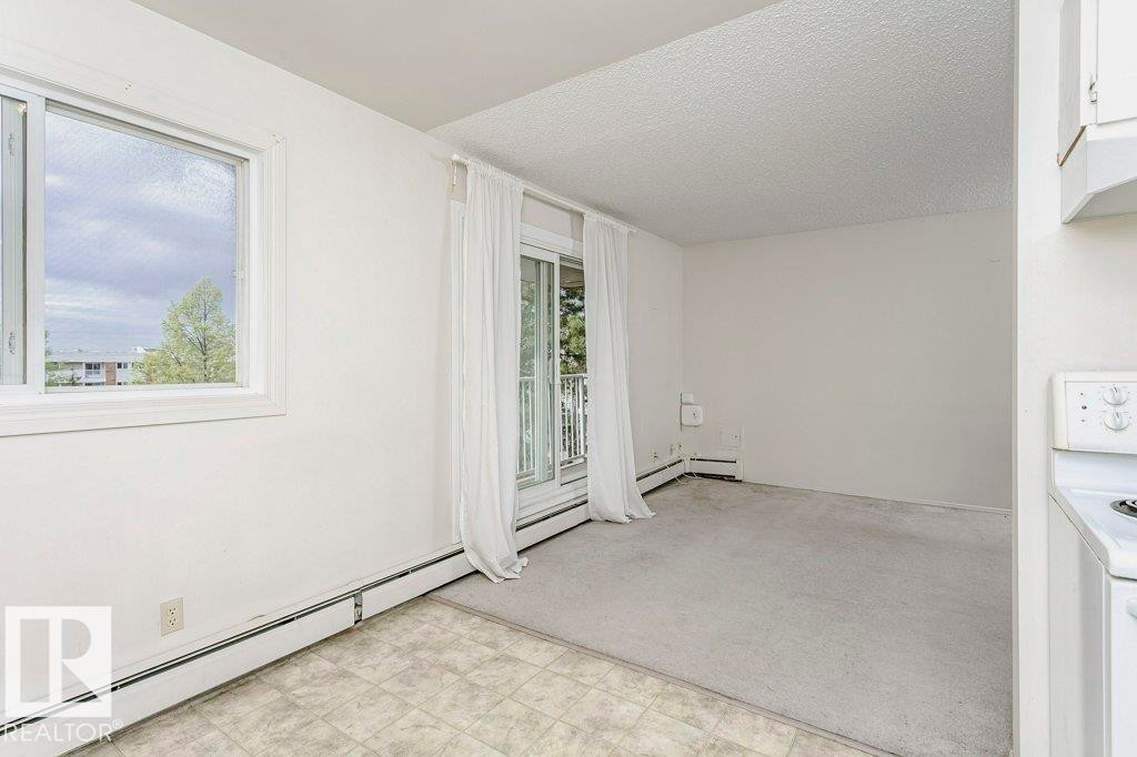Bright interior space featuring a window, sliding glass door with balcony access, wall-to-wall carpeting, and baseboard heating - 71 11255 31 Avenue, Edmonton, AB - Indoor Photo Showing Other Room