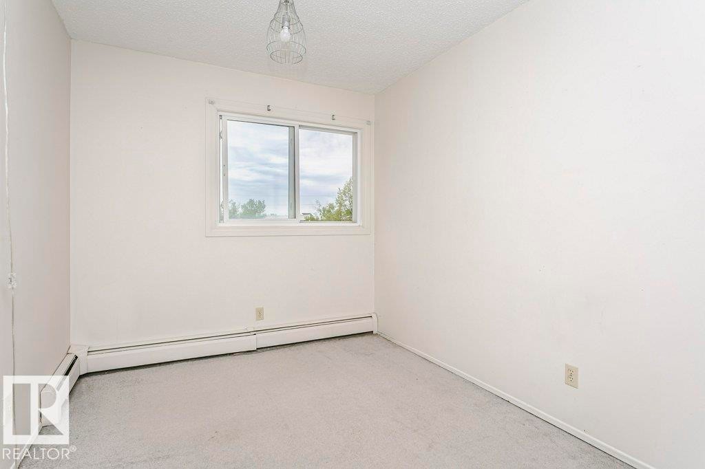 Bright room featuring a prominent window, neutral carpeting, and baseboard heating - 71 11255 31 Avenue, Edmonton, AB - Indoor Photo Showing Other Room