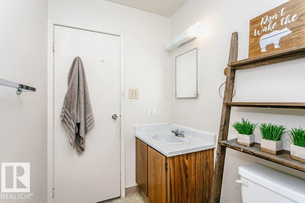 Bathroom vanity featuring a laminate countertop, integrated sink, and wood-finish cabinetry - 71 11255 31 Avenue, Edmonton, AB - Indoor Photo Showing Bathroom