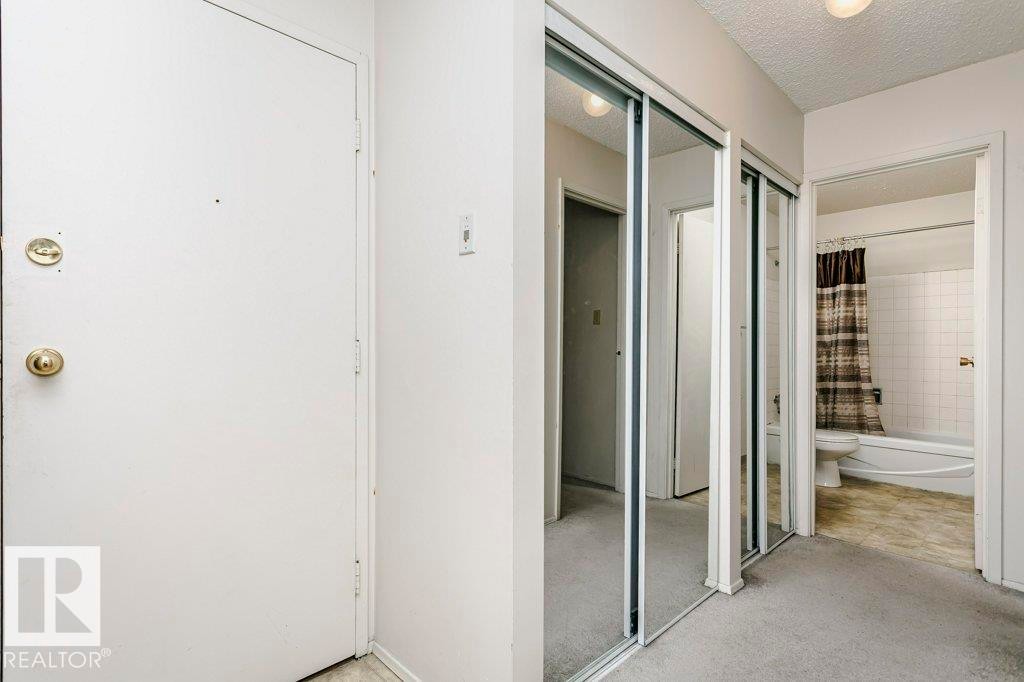 Entryway featuring a white door with brass hardware, mirrored closet doors, and light-toned carpeting - 71 11255 31 Avenue, Edmonton, AB - Photo Showing Other Room