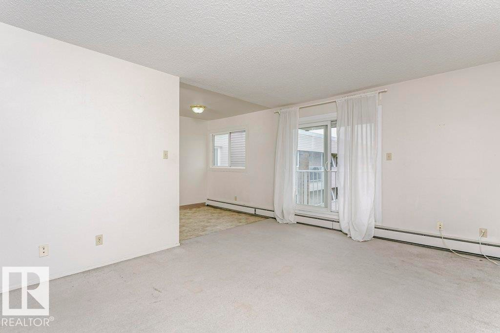 Spacious room featuring light-colored carpeting, white painted walls, and a textured ceiling - 71 11255 31 Avenue, Edmonton, AB - Indoor Photo Showing Other Room