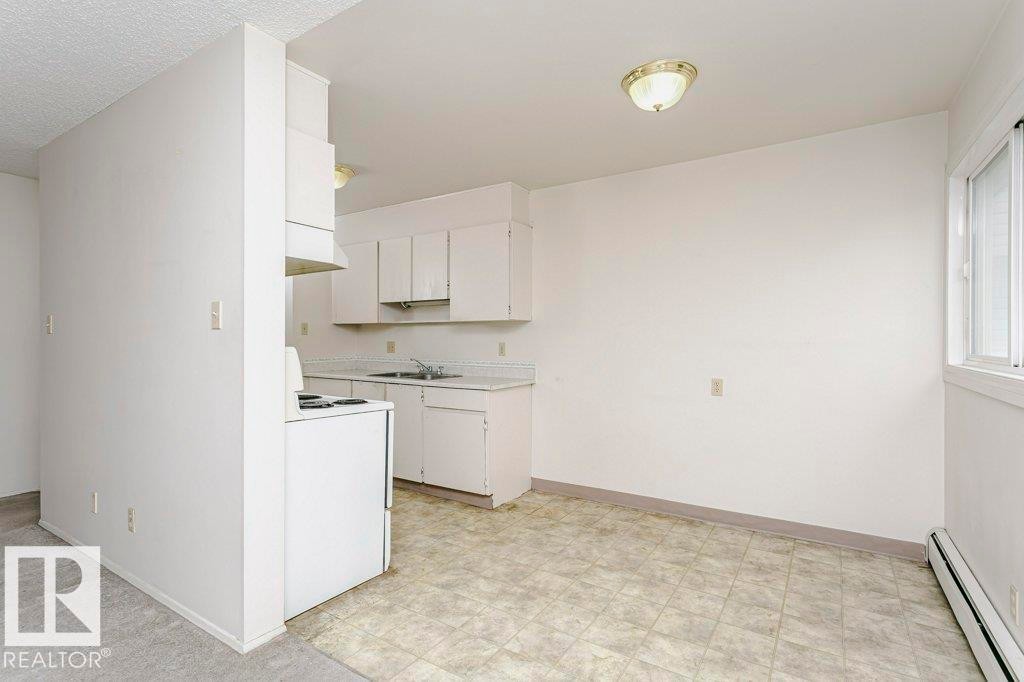 Kitchen area featuring white cabinetry, a double basin sink, and an integrated range hood - 71 11255 31 Avenue, Edmonton, AB - Indoor Photo Showing Kitchen With Double Sink