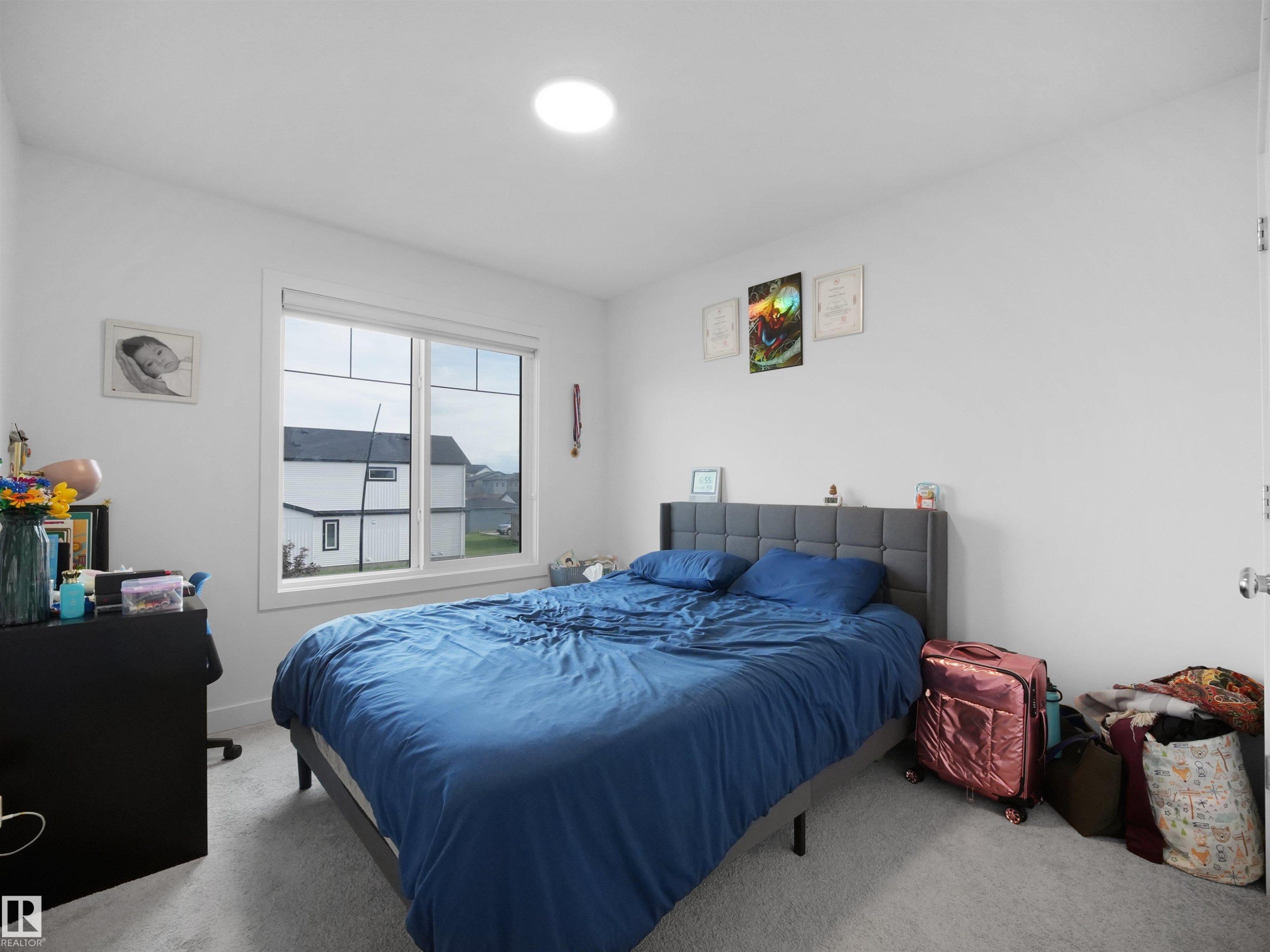 Well-lit bedroom featuring a large window, recessed ceiling light, and light gray wall-to-wall carpeting - 19316 29 Avenue, Edmonton, AB