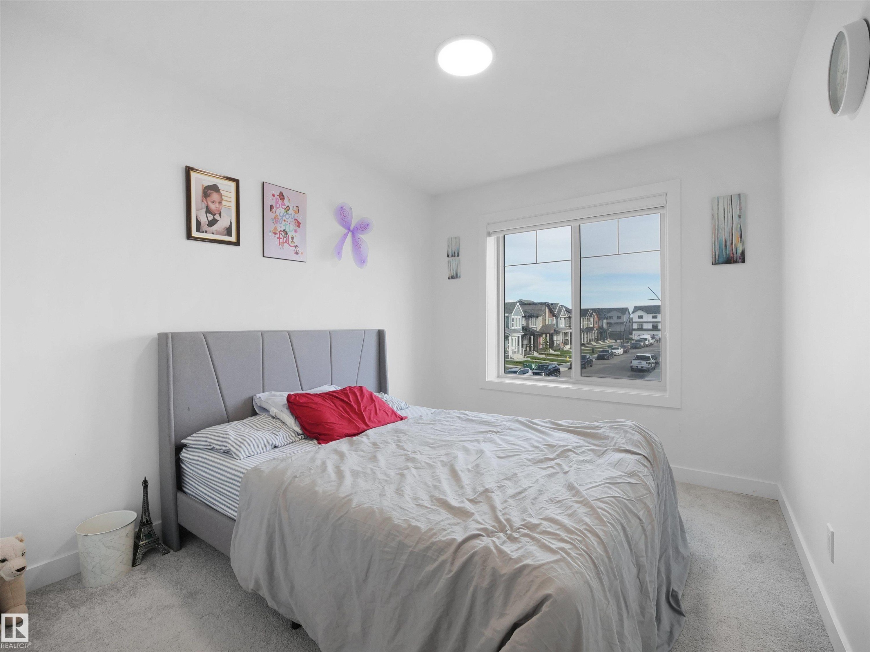 Bright room featuring white walls, a large window, a circular ceiling light fixture, and light-colored carpet flooring - 19316 29 Avenue, Edmonton, AB